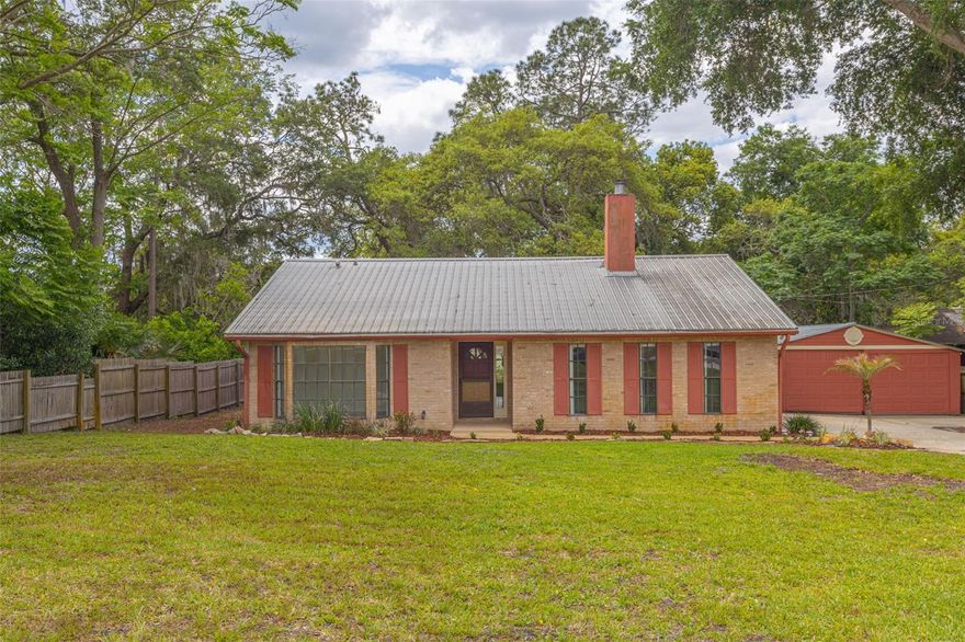 Charming waterfront cottage with a modern feel, offering stunning pond views and beautiful sunset scenery. High vaulted ceilings welcome you into a spacious open-concept great room featuring a cozy fireplace and tile flooring throughout the main living areas. The kitchen is designed for both style and function, showcasing light-colored cabinetry, granite countertops, and seamless flow into the living and dining spaces—all positioned to take advantage of the tranquil water views. The primary suite offers generous space, updated vanities, and a relaxing garden tub. Secondary bedrooms are well-sized, and the additional bathroom includes a full shower and ample room for convenience. Enjoy indoor-outdoor living with a covered screened porch overlooking the water, plus a large yard with plenty of room to add a pool. Car enthusiasts or hobbyists will appreciate the three-car garage setup, including a separate bay ideal for projects or extra storage. A wonderful opportunity to enjoy comfortable waterfront living with modern touches and scenic surroundings.