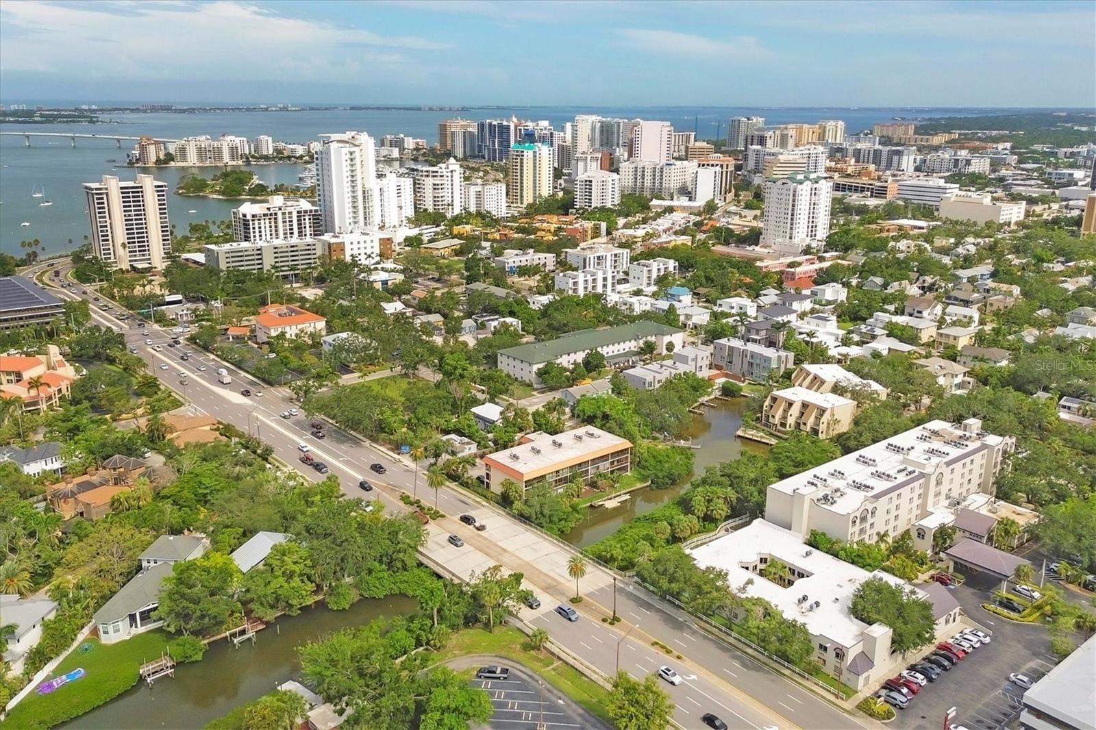 Waterfront and move-in ready, this beautifully updated first-floor condo offers effortless living in one of downtown Sarasota’s hidden gems – Bayou House. Perfectly situated in the heart of the city, yet tucked away on the tranquil Hudson Bayou, this 2-bedroom, 2-bath residence blends modern style with low-maintenance convenience in a prime walkable location. Polished concrete floors, impact windows and sliders, LED ceiling fans and lights, plus an open-concept layout create a clean, modern aesthetic throughout (all updated since 2020). The spacious great room features a wood-beam ceiling detail, sleek track lighting, and large sliders that open to a covered, screened lanai with full-view screen to enjoy calm bayou waters and lush, shaded banks. Fully equipped updated kitchen with soft-close cabinetry, butcher block countertops, subway tile backsplash, LG stainless steel appliances, under-cabinet lighting, and a center island. The primary suite includes direct lanai access, walk-in closet with built-ins, and a stylish ensuite bath with a floor-to-ceiling tiled shower, frameless glass enclosure, and granite countertop vanity. A second bedroom and updated bath provide comfortable space for guests or a home office. Bonus: in-unit Bosch washer and dryer. Bayou House offers assigned parking plus guest parking space, on-site storage, and a private community dock – ideal for launching a paddleboard or kayak right into the Bayou, just strokes from Sarasota Bay. HOA fees include water, trash, sewer, cable, landscaping, and flood insurance for true lock-and-leave ease. Whether you're looking for a full-time residence or a vacation escape, all of downtown Sarasota is at your doorstep. Walk to Selby Gardens, the Bayfront, Marina Jack, Burns Court, galleries, boutique shopping, fine dining, and cozy cafes. Just minutes to Lido Beach, St. Armands Circle and Siesta Key. First-floor, no-step living in the heart of Sarasota, this is Florida waterfront living at its best.