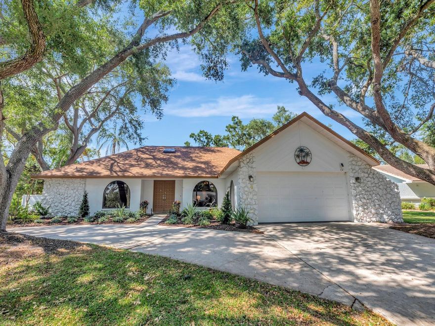 This beautiful split-plan pool home features 4 bedrooms, 2 full baths, and a 2-car garage, all situated on a shaded corner lot. A circular driveway welcomes guests and leads to double front doors opening into a stunning 10' x 10' tiled foyer with a skylight. Roof replaced in 2023 and new carpet installed in 2026.
The spacious layout offers seamless indoor-outdoor living, with the primary bedroom and family room opening directly to the pool area. Double French doors extend the living room outdoors, perfect for entertaining.
The oversized eat-in kitchen is designed for both function and style, featuring stainless steel appliances, granite countertops, deep cabinets, and abundant storage. A kitchen window overlooking the pool includes a pass-through to the outdoor serving bar—ideal for gatherings.
Enjoy the heated lap pool and spa (new pool pump 2026) while relaxing in the inviting family room, highlighted by a floor-to-ceiling stone fireplace with built-in bookcases.
The private primary suite offers direct pool access and includes a spacious bathroom with a Jacuzzi tub, separate shower, and built-in closets, including one walk-in closet with overhead storage.
Step outside to a beautifully paved pool area designed for entertaining. The covered lanai accommodates multiple seating arrangements and provides the perfect space for outdoor dining and grilling. Lush, established landscaping creates a true tropical oasis, enhanced by a zoned irrigation system and outdoor solar lighting.
Conveniently located approximately 30 minutes from Tampa International Airport, 20 minutes from Clearwater Beach, and 15 minutes from Tarpon Springs and its famous Sponge Docks.
