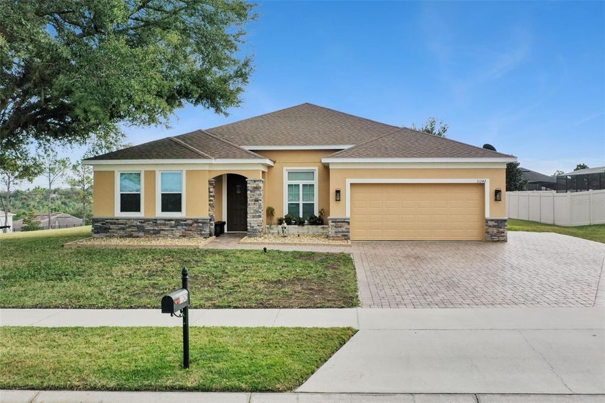 Enjoy beautiful views of the rolling hills of Clermont in this stunning 5-bedroom/3-bathroom home with 2,575 sq. ft.Built in 2014, this home is in the highly desired community of Vista Grande on a large lot. Enjoy extra parking in the extended paved driveway on the side of the house, beautiful landscaping, and shade from a mature oak trees out front and out back. Inside you will find a great open floorplan featuring formal dining, a spacious living room, and a gourmet kitchen at the center of the home.The kitchen features granite countertops, stainless steel appliances, cabinets with crown molding and a large kitchen island overlooking the family room. The living room has plenty of natural light and doors to the lanai and extended pad out back. The bedrooms are split, and the master suite is located near the back of the home. It has tray ceilings with crown molding, and a beautiful master bath with granite countertops, dual vanities, walk-in shower, garden tub, and large walk-in closet. There is a bedroom near the front of the home with a guest bath making it a perfect place for company or an in-law suite with its own space at the front of the house with a full small kitchen. Three more bedrooms are located on the opposite side of the home, giving plenty of privacy for everyone. Relax on the lanai and extended pad and watch the beautiful Florida sunsets, sunrises and/or Disneys fireworks at night! This home has been meticulously well maintained with a 2 year old roof, sealed pavers, exterior paiint redone (2023), replaced flooring in front bedroom to vinyl planks and two other bedrooms with wood flooring. This home won't lasts long so set up your private showing today!