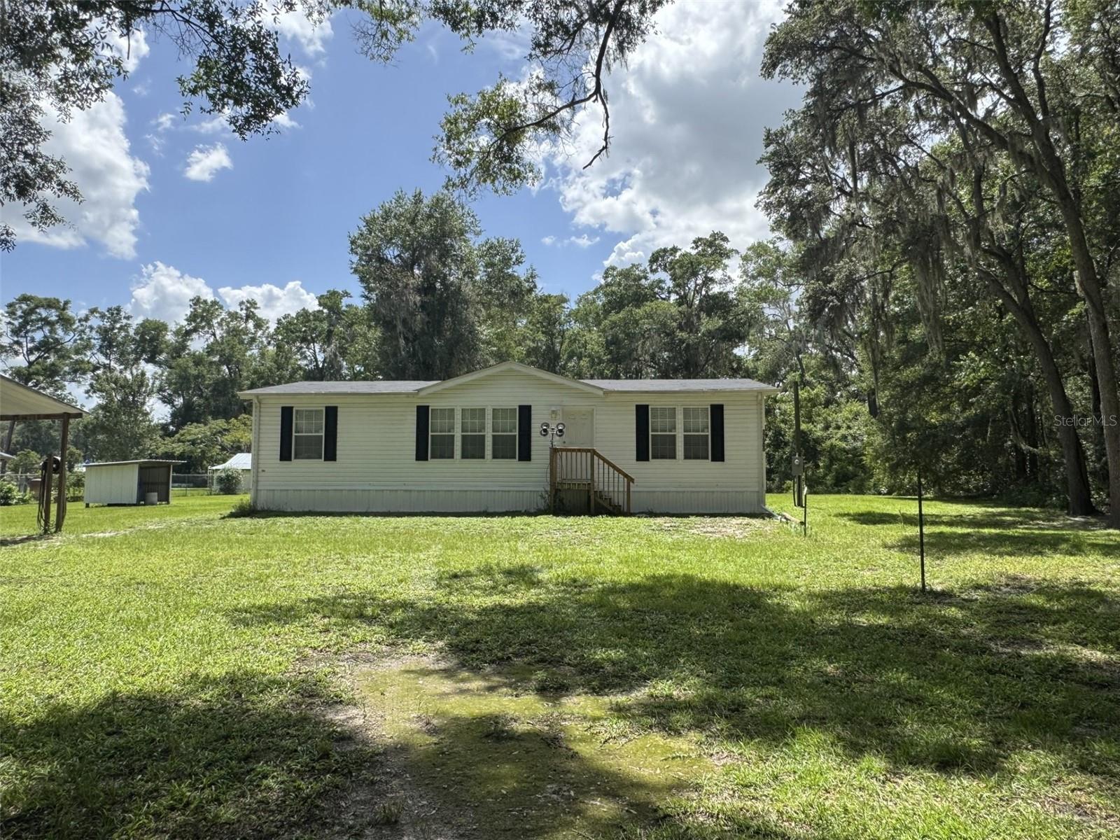This newer 3-bedroom, 2-bath manufactured home sits on a spacious and picturesque 0.98-acre lot, offering the perfect blend of open-concept comfort and rural tranquility. Step inside to an inviting split floor plan featuring a well-sized kitchen with a peninsula for bar seating, an eat-in dining area, and a cozy living room ideal for entertaining.
The primary suite boasts a generous bedroom, walk-in closet, and a well-appointed en-suite bath with a walk-in shower, vanity with ample counter space, and a built-in open linen closet. On the opposite end of the home, you'll find two additional bedrooms, both with walk-in closets, a full guest bath with a shower/tub combo, and a dedicated laundry room with shelving.
Outdoors, enjoy a lush green yard with partial fencing, a covered well house including the water softener , and an open pole barn perfect for vehicles, a boat, or equipment. Rain gutters are already in place for added convenience. Tucked away in a quiet, rural setting, this property provides peaceful living just a short drive from shopping, medical facilities, and The Villages. A must-see for those seeking space, functionality, and a touch of country charm.