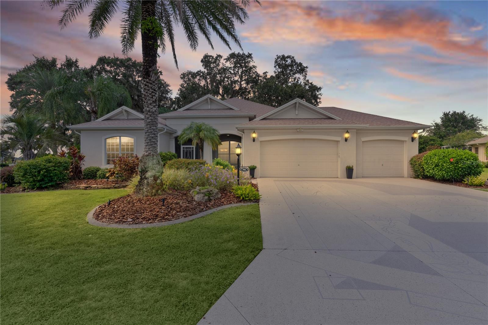 Experience the essence of “Living the Dream” in this meticulously maintained 3-bedroom, 2-bath Williamsburg PREMIER HOME, perfectly situated in the highly sought-after Village of Bridgeport at Lake Sumter. Located in Florida’s most desirable golf community—with NO BOND—this home offers timeless elegance and modern upgrades, including a newer roof (2022), freshly painted interior, stainless steel appliances with a new microwave (2025), dishwasher (2025), and a newer refrigerator (2023). Granite countertops, NO CARPET, and a versatile bonus room off the primary suite (ideal for an office or gym) add to the appeal. The thoughtfully designed split floor plan is perfect for entertaining, featuring a kitchen that flows seamlessly into the spacious dining and living areas with soaring 10-foot ceilings. The living space opens onto a wraparound patio overlooking lush landscaping and mature trees, enhanced by extensive exterior lighting—an inviting setting for both relaxation and gatherings. The primary suite impresses with tray ceilings, dual walk-in closets, and a spa-inspired en-suite bath offering dual vanities, a Roman shower, and a luxurious garden tub. Additional highlights include a garage designed to accommodate two cars plus a golf cart, a painted driveway with ample parking, and updated plumbing fixtures (2025). Furniture and Golf Cart Package is available separately. With room for a pool and a prime location just 3 minutes from Lake Sumter Landing Square and 1 minute from Palmer Country Club & Golf Course, this property perfectly blends convenience, lifestyle, and elegance. Schedule your private tour today and make this dream home yours!