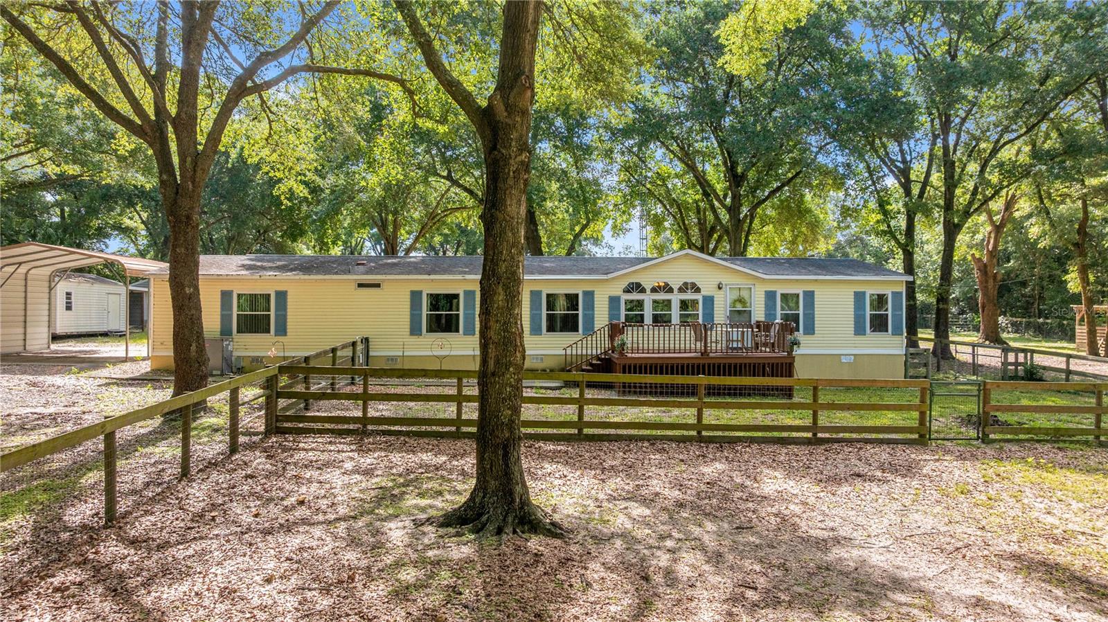 Welcome to your dream mini farm, just one block from beautiful Lake Weir in Ocklawaha, Florida! This charming 4-bedroom, 2-bathroom home offers 2,052 square feet of inviting living space on a fully fenced and ready-to-go 3-acre parcel—perfectly tailored for equestrian lovers. The property is fully outfitted for horses with a 4-stall shed-row barn featuring a concrete center aisle, air-conditioned tack room, hot and cold water, and its own washer and dryer setup. Each stall opens directly to a paddock, and the land includes four fenced paddocks/pastures and three water sources, making horse care effortless. Sit back and enjoy the peaceful views from the front deck overlooking the paddocks, or wind down on the rear screened-in porch with a view of the barn and pastures beyond. Inside, you’ll find a thoughtfully laid out floor plan with a spacious primary suite boasting dual walk-in closets and a standalone shower. One of the guest bedrooms conveniently connects to a bathroom, while two additional bedrooms offer plenty of space for family or guests. The heart of the home is the remodeled kitchen, complete with real wood cabinetry, granite countertops, and all the cozy farmhouse vibes. Additional highlights include a formal dining room, living room, and separate family room, as well as an oversized laundry room that doubles as a mudroom—ideal for life on a farm. You’ll also enjoy carport parking, two large storage sheds, a 2019 AC, and the peace of mind of a brand-new roof to be installed by the seller prior to closing. The grounds are dotted with mature trees and beautifully maintained, offering the perfect blend of function and beauty in a rural setting.
This turnkey property is ready for you and your animals—don’t miss the opportunity to make this slice of country paradise your own!