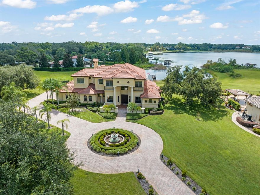 Tucked inside one of Windermere’s most exclusive guard-gated communities, this extraordinary custom-built estate is more than a home — it’s a destination. With almost 6000sq. ft., six bedrooms, six and a half baths, a detached in-law suite, and nearly two acres of pristine lakefront land, it represents the pinnacle of Central Florida luxury. Set on a quiet cul-de-sac, the residence blends timeless craftsmanship with modern amenities, offering both privacy and grandeur. Whether you seek a multigenerational sanctuary, an entertainer’s retreat, or a tranquil everyday escape, this property delivers it all. A winding driveway welcomes you to landscaped grounds framed by mature trees and sweeping lawns. The nearly two-acre lot is a rarity in Windermere, offering openness and privacy rarely found in guard-gated communities. At the water’s edge, a private dock provides access to a private ski lake — perfect for boating, skiing, or sunset cruises.
As night falls, the skyline transforms into your own private theater. From your backyard or expansive picture windows, you’ll enjoy nightly fireworks from Walt Disney World — an exclusive show few homeowners can claim. Thoughtfully designed to maximize the lot and views, the home emphasizes connection to nature with soaring ceilings and picture windows that frame the lake. Light-filled open spaces invite both lively gatherings and peaceful mornings. Inside, the foyer flows into a spectacular living room anchored by lake views. The chef’s kitchen features custom cabinetry, high-end appliances, and an oversized island, opening seamlessly to dining and living spaces. Every meal, whether casual or elegant, is elevated by sweeping water vistas. The primary suite, located on the main floor, is a true haven with direct outdoor access and serene lake views. The spa-like en-suite features a soaking tub, dual vanities, and walk-in shower, with abundant closet space for ultimate convenience With 6 bedrooms and 6.5 baths, the home balances elegance with flexibility. The detached in-law suite — complete with separate entrance, living area, bedroom, and bath — is ideal for aging parents, adult children, guests, or even a private office. Offering both independence and connection, it defines multigenerational living at its best.
Whether hosting indoors in the great room and chef’s kitchen, or outdoors along the lake, this home was made for unforgettable gatherings. Picture holiday dinners, lakeside barbecues, or evenings with wine as fireworks reflect across the water
Land is everything, and this nearly two-acre property is extraordinary. With ample room for future additions — from a resort-style pool to lush gardens — it offers a rare blend of seclusion, space, and lakefront access. Located in one of Windermere’s premier guard-gated neighborhoods, residents enjoy 24/7 security, prestige, and community pride. Windermere itself is among Central Florida’s most coveted addresses, known for top schools, charming character, and easy access to Orlando’s business and entertainment hubs. This estate is defined by its nightly show — fireworks lighting up the lake from Disney. More than a view, it’s a lifestyle: mornings on the dock, afternoons on the water, evenings under a glowing sky. This isn’t just a home. It’s an escape, a sanctuary, and a stage for life’s best moments. For those seeking a property that combines size, luxury, flexibility, and exclusivity, this Windermere estate is unmatched.