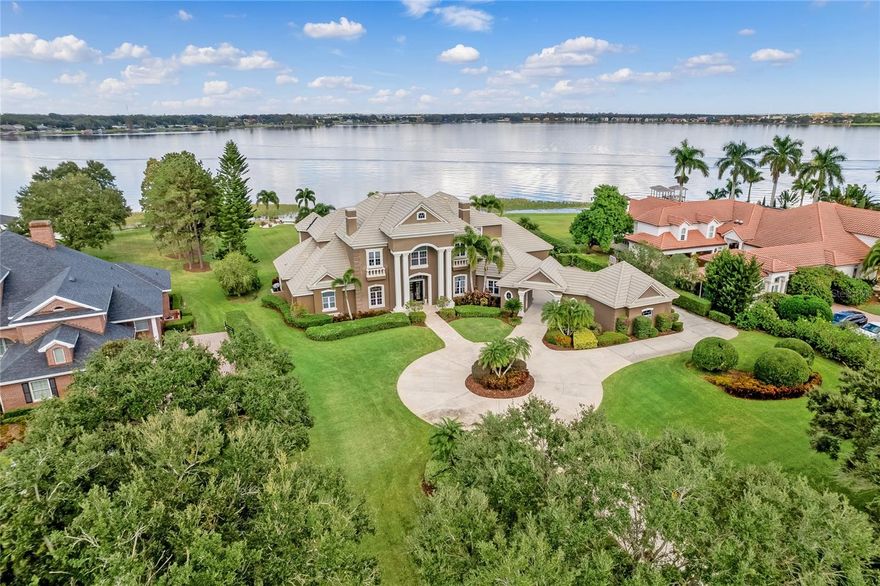 Experience ultimate luxury in this lakefront estate situated in Wyndham at Lake Winterset, a secure gated and guarded community on the Winter Haven Chain of Lakes. Set on an expansive 1.45-acre lot, one of the largest lots on Lake Winterset, this dream home seamlessly offers serenity and natural beauty. With 4 bedrooms (all with en-suite bathrooms), 4 full baths, 2 half baths, an executive office, a game room, bonus room, craft room and over 6,882 sqft of living space, this residence is impressive both inside and out. Upon entering the grand foyer, you'll be captivated by the sweeping views of the tranquil waterfront through the expansive windows. Elegant formal living and dining spaces, complemented by a full wet bar and wine room, create a perfect backdrop for entertaining and spending quality time with loved ones. The well-appointed kitchen boasts top-tier stainless steel appliances, double ovens, custom cabinetry, granite counters, a spacious island, walk-in pantry and a dinette area with a view of the pool and lakefront. Adjacent to the kitchen, a family room features custom built-ins, gas fireplace and a wall of corner glass sliders that fully open allowing seamless entry to the outdoor living spaces. The ground floor primary suite is a haven of tranquility, offering a sitting area, two magnificent walk-in closets, exercise room, and breathtaking lake views. The en-suite master bathroom is a luxurious oasis with travertine flooring, jetted soaking tub, large walk-in shower and dual vanities. An executive office, powder room, pool bath and laundry room complete the ground floor. The guest bedrooms are located on the second level, each with their very own en-suite bathrooms, comfortable dimensions, and generous closet space. Two of the bedrooms share access to a bonus room overlooking the lake, ideal for a kids' hangout, theater, or secondary living space. Upstairs is also home to a full game room complete with a full bar, billiards, and a card table. You will also find a craft room featuring extensive cabinetry and storage. The outdoor area radiates a luxurious resort ambiance, boasting travertine stone pavers, expansive covered spaces, ample room for sun-soaking and an oversized pool featuring a spa, sun shelf and a captivating fire element. All of this is set against the backdrop of 170 feet of pristine lakefront. Walking down to the lake, you'll discover a white sand beach area for lakeside lounging, crystal clear waters, and a dock with a covered boat lift. Living on the Winter Haven Chain of Lakes allows you to indulge in boating, skiing, and fishing on over 20 interconnected lakes. During special occasions, your backyard becomes the perfect vantage point to enjoy the Legoland fireworks show, adding an extra touch of magic to the already mesmerizing atmosphere. Additional features include 4 full sized garage spaces, an outdoor sauna room and a community tennis court and playground. Located less than 1 hour from Disney World, 1.5 hours to Orlando International Airport (MCO) and Tampa International (TPA) - close to shopping, dining and more, living in Winter Haven provides residents with a fantastic quality of life and endless opportunities for adventure and relaxation. Embrace the allure of lakefront living today! Schedule a showing now and discover the boundless potential of calling this Central Florida lakefront property your forever home.