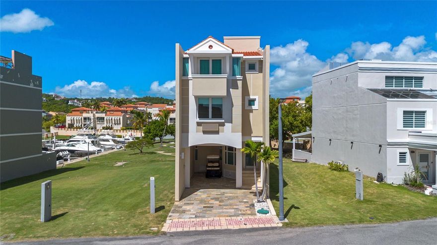 Live the ultimate coastal lifestyle in Peninsula de San Juan, an exclusive waterfront enclave within Palmas del Mar. Home to only 25 private residences, this gated community offers privacy, security, and direct access to the open sea. This stunning four-story home features 5,136 square feet of total construction, with 3,652 square feet of elegant living area. A highlight of the property is its private boat slip, complete with a concrete walkway, access deck, water and power connections, offering effortless access to the bay and open waters. Ideal for those who love life on the water, this unique setup lets you go from your doorstep to your boat in just minutes. Spend your days sailing, fishing, or discovering the coastline — here, every outing feels effortless and every return feels like home.
Inside, you’ll find high ceilings, bright and airy spaces, and a thoughtful layout with 4 bedrooms, 4 bathrooms, an elevator connecting all levels, and a spacious family room on the lower floor. The deck overlooking the water and docks offers the perfect setting to entertain or unwind while enjoying the coastal breeze.
Residents of Peninsula de San Juan enjoy 24-hour security, as well as all the world-class amenities Palmas del Mar has to offer—restaurants, marina, golf courses, tennis and pickleball courts, equestrian center, school, beach club, shopping center, and more. Experience Caribbean living at its finest in this rare waterfront opportunity.