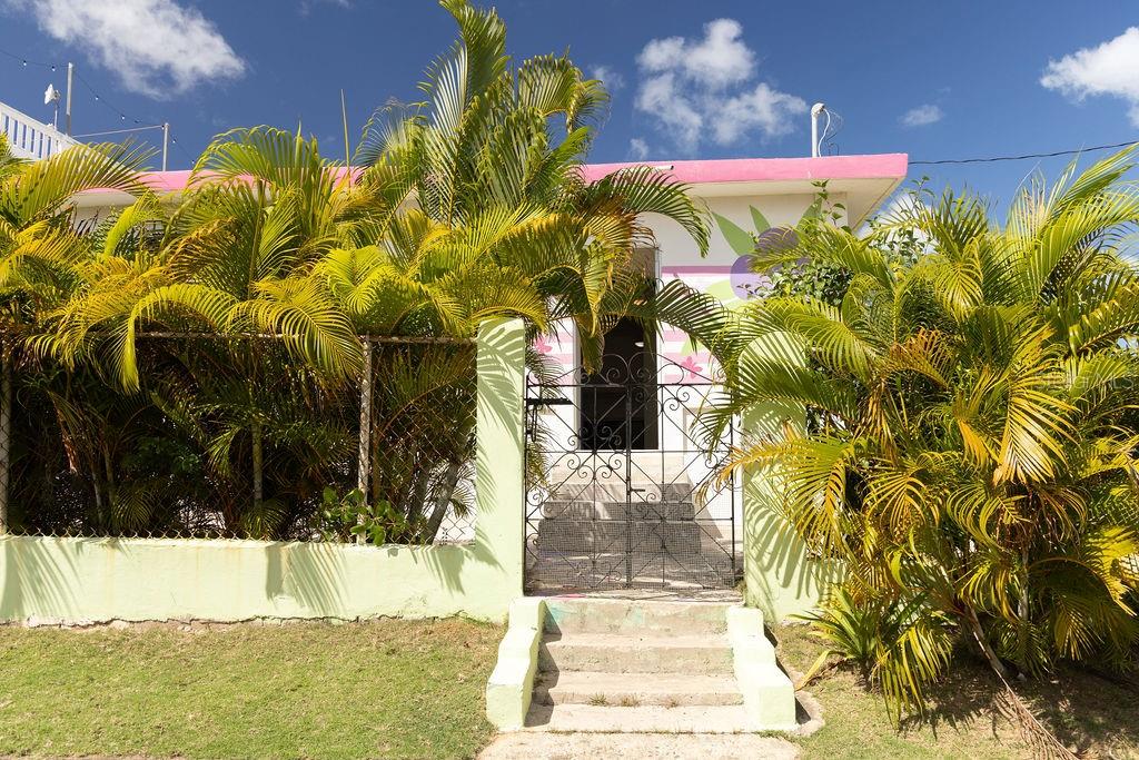 This cute two-building compound is conveniently located in the centric neighborhood of Monte Santo Playa. Thoughtfully landscaped grounds provide privacy from the street, while the detailed and whimsical paintwork and materials add character to the functional spaces.
The main house features a foyer, spacious living room, kitchen, three bedrooms, and one bathroom. A lovely central garden with a perfectly manicured lawn separates the house from the freestanding studio, which includes its own kitchenette and bathroom.
The property also has a private carport and outdoor storage, which can be easily converted into a laundry room. Extremely well-maintained, ready to move in, and less than a ten minute walk to the farmer’s markets, bars, restaurants, and a supermarket.