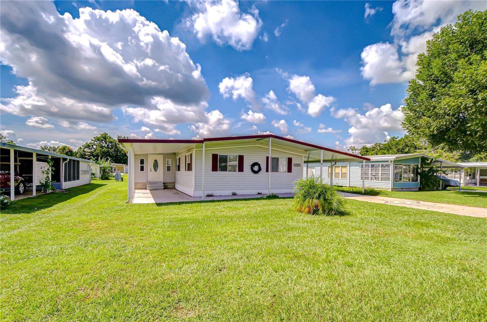 NESTLED IN DESIRABLE 55+ COMMUNITY: with larger lots than most parks, this spacious 3 bedroom, 2 bath double wide is ideal for year-round living or the perfect winter nest to escape the snow. The home features a cozy dinette with built-in china cabinet off the kitchen, a formal dining area for larger gatherings, a finished Florida room for extra space, an updated kitchen with stainless steel refrigerator and built-in microwave, Also an updated bathroom. Accented with laminate and LVP flooring throughout, the home also offers room for 2 cars and a golf cart under the carport, with a utility/shop conveniently located at one end. This active community has NO lot rent, and the low yearly fee covers your water. Pet friendly! Close to restaurants, grocery stores, medical facilities, and even a movie theater, this home combines comfort, convenience, and value in a vibrant setting.