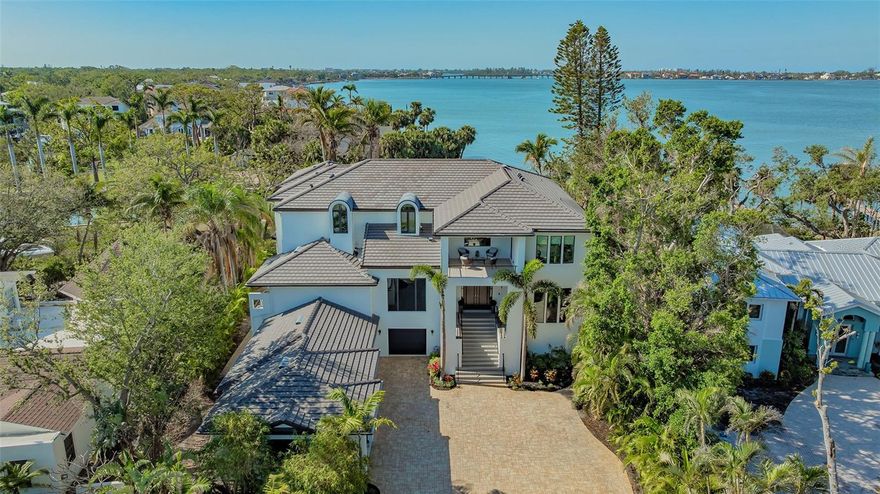 This exceptional 4-bedroom, completely renovated in 2020, highlights this waterfront estate in prestigious Harbour Acres offering 100 feet of prime Sarasota Bay frontage with private dock and lift. This masterpiece features 7074 Sq ft of living space with sweeping Bay views, a light filled open floor plan, and exceptional indoor-outdoor flow.

A grand entry with dramatic staircase, opens to expansive living and dining areas, framed by floor to ceiling windows overlooking the water. The Italian modern gourmet kitchen offers premium Miele appliances, generous island seating, and a striking double sided gas fireplace shared with the living room - ideal for entertaining. This home provides rare flexibility with primary suites on both the main and upper-level levels, each with en suite baths and walk-in closet, along with additional guest suites, private office, sophisticated wine room, elevator, and dedicated fitness room. 
Outdoor living is a highlight, featuring a saltwater pool and spa, multiple terraces, outdoor kitchen, and professionally landscaped grounds leading to a concrete seawall and boat dock with a 30,000 pound boat lift, electric, water and fish cleaning station.
Southwest exposure delivers stunning sunsets and quick access to Sarasota Bay.
Spacious four-car garage complete with an electric charging station - this estate seamlessly blends opulence with modern convenience.
Perfectly situated near Sarasota‘s renowned beaches, fine dining, vibrant arts scene, and top-tier medical facilities, this residence offers an unparalleled living experience in one of the most coveted waterfront communities.