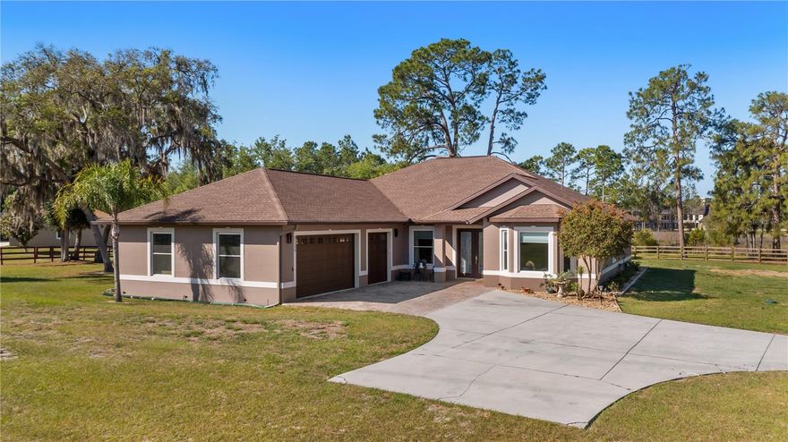 Privacy and comfort come together beautifully in this custom-built home on 2.72 open acres in sought-after Arrowtree Reserve. Surrounded by mature trees and wide open space, this property offers the peaceful lifestyle you have been looking for with the sounds of birds and wildlife all around, while being just two minutes from the Florida Turnpike for easy access to Orlando and beyond. As you arrive, the fully fenced grounds with a personnel gate and driveway gate immediately set the tone for privacy and security. The home itself spans 2,676 square feet and showcases quality craftsmanship throughout, including detailed crown molding and beautifully designed tray ceilings that elevate each living space. Inside, the layout offers flexibility and function with an oversized family room, a formal living room with a fireplace, and a separate formal dining room that is ideal for entertaining. A dedicated office or den provides space to work from home, while the breakfast nook and bar seating create a warm and inviting everyday gathering area. The chef’s kitchen is the heart of the home, featuring a gas range, built-in oven and microwave, a large work island with sink, granite countertops and an oversized pantry with exceptional storage. Every detail has been thoughtfully designed for everyday living and hosting. The primary suite is generously sized and offers a retreat with dual walk-in closets and a spacious en-suite bath complete with double vanities and a whirlpool jetted tub. Secondary bedrooms are oversized and provide comfort and flexibility for family or guests. Go outside to the large covered and screened lanai, a perfect extension of the living space where you can bring your grill or flat top griddle and enjoy outdoor cooking while taking in the peaceful surroundings. With direct access to a full bath, this area is ideal for entertaining or relaxing year-round. Additional features include an oversized three-car garage that is under air, an RV parking pad, tankless water heater, whole-house generator, and lifetime warranty on all windows. The home is extremely energy efficient, offering comfort and long-term savings. In Arrowtree Reserve, residents enjoy a unique blend of luxury and rural charm. This equestrian-friendly community is known for its large acreage homesites, scenic riding and recreational trails, and a sense of space and tranquility that is increasingly rare. Despite its peaceful setting, you remain close to shopping, dining and major roadways, making it easy to enjoy privacy and convenience. This is more than just a home, it is a lifestyle defined by space, nature and refined living in one of the area’s desirable communities.