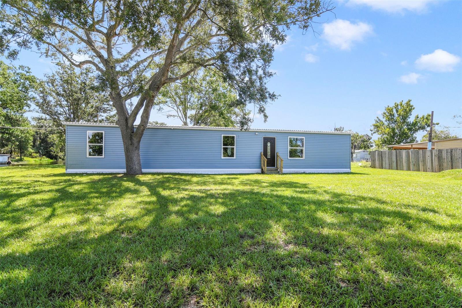 This beautifully remodeled 4-bedroom, 2-bathroom manufactured home with lake view offers the perfect blend of space, comfort, and style — all while sitting on its own private land (no lot rent!). From the moment you walk in, you’ll be impressed by the modern updates and spacious layout.
The home features a brand-new kitchen with stylish cabinets, countertops and plenty of storage space. Both bathrooms have been fully renovated, including contemporary vanities, updated fixtures, and elegant tile work. The open floor plan offers generous living and dining areas, perfect for entertaining or everyday living. The primary bedroom suite includes a walk-in closet and a private en-suite bathroom. All four bedrooms are spacious and filled with natural light. Additional highlights include: New laminate flooring throughout, New doors and windows, New roof, New AC, Fresh interior and exterior paint, Updated lighting, Indoor laundry room, Large yard with room to garden, park vehicles, or add a shed. Located in a quiet, established neighborhood with no HOA, this home is move-in ready and ideal for families, investors, or anyone looking for a comfortable home with land ownership included. Call your Realtor today to schedule an appointment.