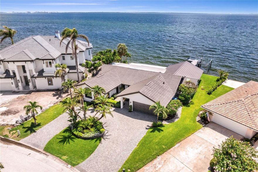 Welcome to the pinnacle of waterfront luxury living in the highly sought-after, deed-restricted community of Venetian Isles. Perfectly situated on an expansive 133 feet of deep sailboat water frontage, this exceptional home offers direct access to Tampa Bay and the Gulf of Mexico with no fixed bridges—making it an ideal setting for boating enthusiasts. Every sunrise brings a new masterpiece across the bay, while cool evening breezes and shimmering city lights of Tampa provide a magical backdrop for coastal living.
A graceful circular Belgium Cobblestone driveway, complemented by lush tropical landscaping and a covered courtyard entry, sets the tone for the elegance that awaits inside. Step into a beautifully designed interior where nearly every room is oriented to maximize the stunning water views. The waterfront living room and the air-conditioned Florida room invite relaxation and effortless entertaining, both overlooking the sparkling swimming pool and open bay beyond.
The heart of the home is a chef’s dream—an exquisitely remodeled kitchen featuring top-of-the-line appliances, a gas stove, custom wood range hood, an oversized center island, and a wine refrigerator. Designed with both functionality and beauty in mind, the space is perfect for preparing meals or gathering with guests in comfort and style.
The expansive master suite is a true retreat, offering two spacious walk-in closets (including one large enough to serve as a nursery, office, or gym), a massive sitting area, space for a wet bar, and a wall of glass that captures sweeping, uninterrupted views of the bay. It’s a personal sanctuary where you can wake each morning to the tranquil beauty of the water.
Outdoors, enjoy a resort-style experience with a pristine swimming pool, covered alfresco dining area, and a private dock that stretches into the bay. The wide seawall adds to the sense of openness and security, while the dock is ideal for launching your boat or simply enjoying the peaceful ambiance of life on the water.
Renovated to perfection and offering remarkable water views from multiple rooms, this home is ideally located just minutes from downtown St. Petersburg. Whether you choose to arrive by bike, golf cart, or boat, you’ll enjoy easy access to award-winning dining, arts, and entertainment. The proximity to I-275, Tampa International Airport, and our world-famous white sand beaches ensures that convenience matches luxury at every turn.
This is more than a home—it’s a waterfront lifestyle unmatched in beauty, comfort, and location. Come discover why so many choose to call Venetian Isles home. *The Allstate flood insurance is assumable @ roughly $900 a year. See attachments.