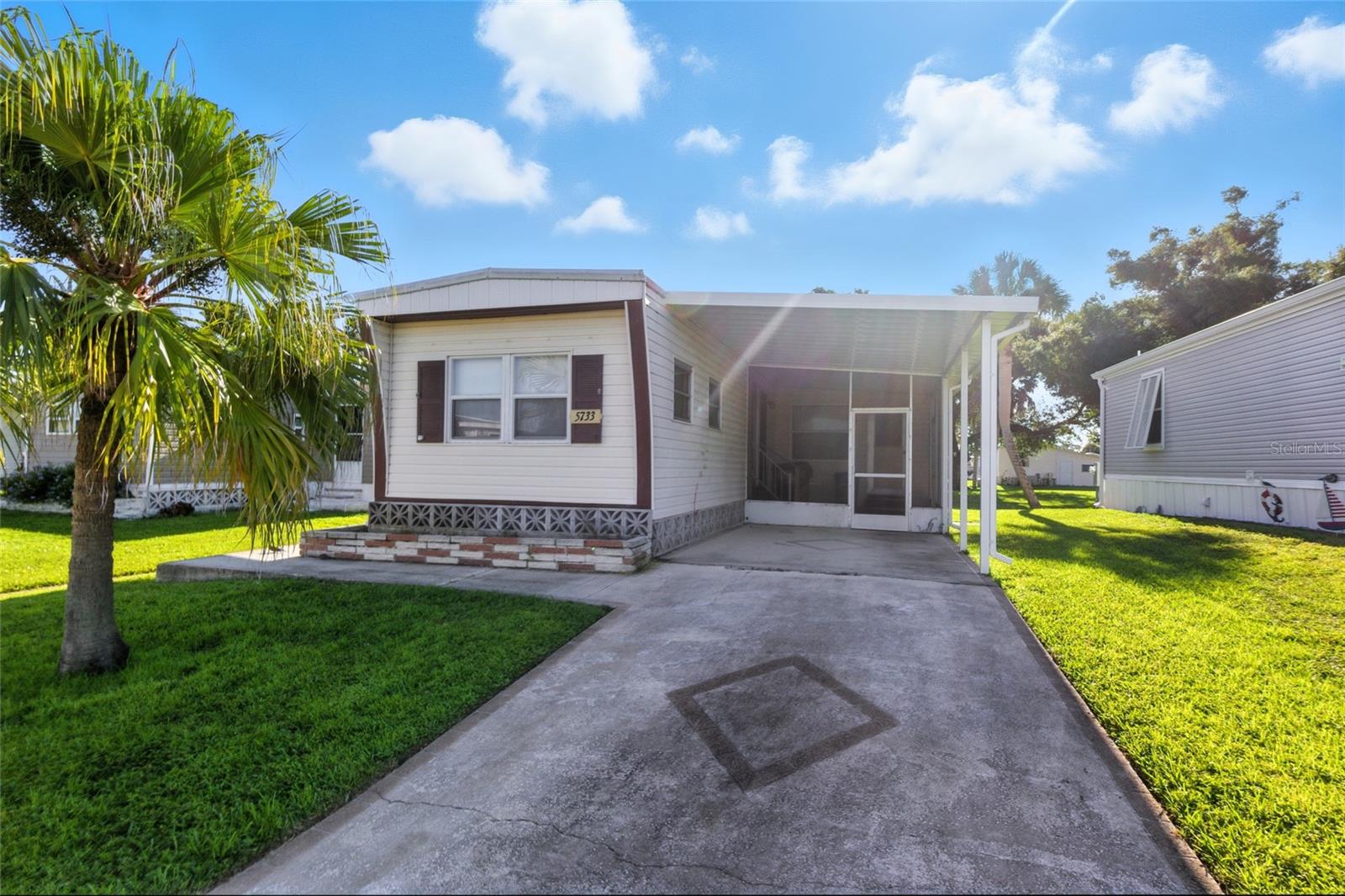 This cozy 2 bedroom, 2 bathroom mobile home is located in Holiday Park, a much sought after 55+, land owned, gated community in the heart of North Port. Your furry friends are welcome as this property is located in the highly desired PET SECTION. The home comes fully furnished, with indoor laundry and all kitchen appliances. A/C was replaced in 2024, new carpets added, and a propane tank was added to the property in 2018 which was recently filled and will convey full. Enter through the front door and you'll be greeted by the living room to your right and an open concept eat-in kitchen with a peninsula to your left- an awesome layout for entertaining, you'll never be too far from your guests! Past the kitchen and down the hall lies your primary bedroom (with laundry inside, how convenient!) with an en-suite bathroom, and the guest bedroom and bathroom. Off the living room, you'll have a screened lanai-a perfect spot to enjoy the outdoors! Outside towards the back of the home, there's a green space with mature, shady trees which creates a buffer of privacy between you and your back neighbors. You'll also have your carport and shed for storing your extra things. The community features two clubhouses, two swimming pools, a library, a fitness center, tennis, pickleball & bocce ball courts as well as a storage facility where you can store boats, campers, or anything else you need storing, at no additional charge. You'll also find billiards, shuffleboard, horseshoe pits, ping-pong tables, a card room and social activities, all at your fingertips. Your next home awaits you!!