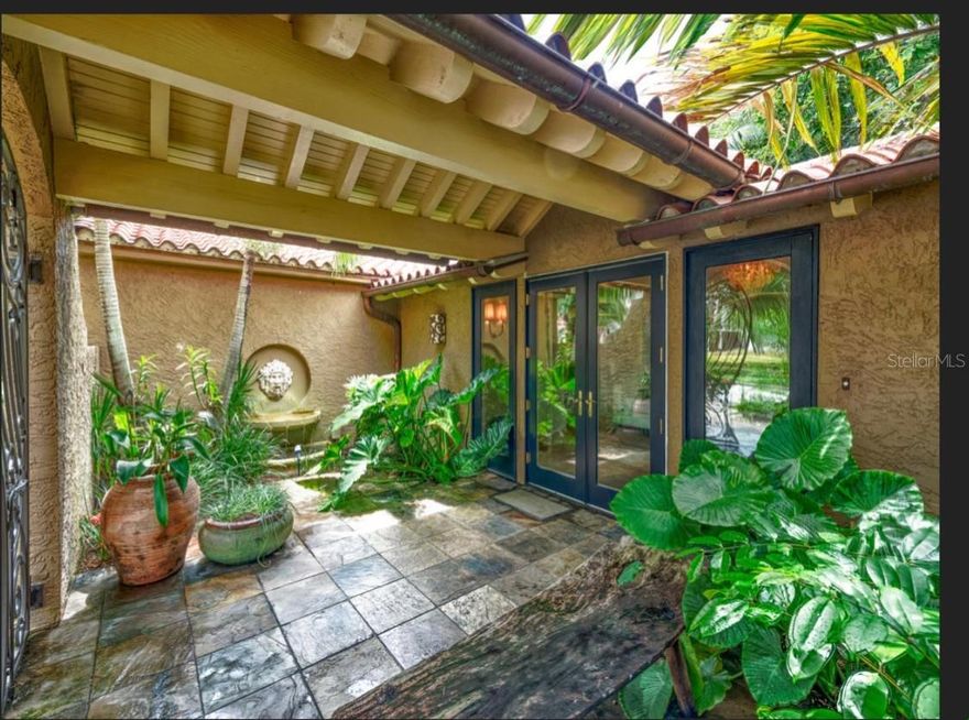 Hidden just beyond a canopy of lush tropical landscape on iconic Brightwaters Blvd NE, this refined 2,800 sq ft courtyard-style bungalow reveals a serene, resort-inspired sanctuary. Through dramatic wrought-iron gates, a beautifully curated interior unfolds—sun-drenched, elegantly proportioned, and designed with an effortless sense of sophistication. The reimagined kitchen showcases a sleek neutral tile backsplash, a generous free-standing island, gas stovetop, Sub-Zero refrigerator, wine fridge, and an impressive walk-in pantry—perfectly blending style with chef-level functionality. Thoughtfully placed windows and French doors invite tranquil courtyard vistas and the soft sound of water features into the home, creating a seamless connection between indoor comfort and outdoor serenity. The expansive primary suite is a private retreat of its own, tucked toward the rear of the residence with French doors opening directly to the lush backyard oasis. Outside, indulge in the tranquility of your secluded cabana with a gas fireplace, charming fountains, and a large pool enveloped by mature tropical landscaping—an idyllic setting for both intimate evenings and elevated entertaining. Additional enhancements include four spacious bedrooms and three spainspired baths with oversized walk-in showers, custom California Closet systems, a full-home stereo system, a decorative interior fireplace feature, a propane gas hot water heater, and a new reverse osmosis and whole-house water filtration system. The home is also pre-wired for an infrared sauna, offering yet another luxurious touch. Situated on one of Pinellas County’s most coveted streets, this exceptional courtyard residence offers an extraordinary blend of privacy, elegance, and resort-style living—certain to captivate even the most discerning buyer.