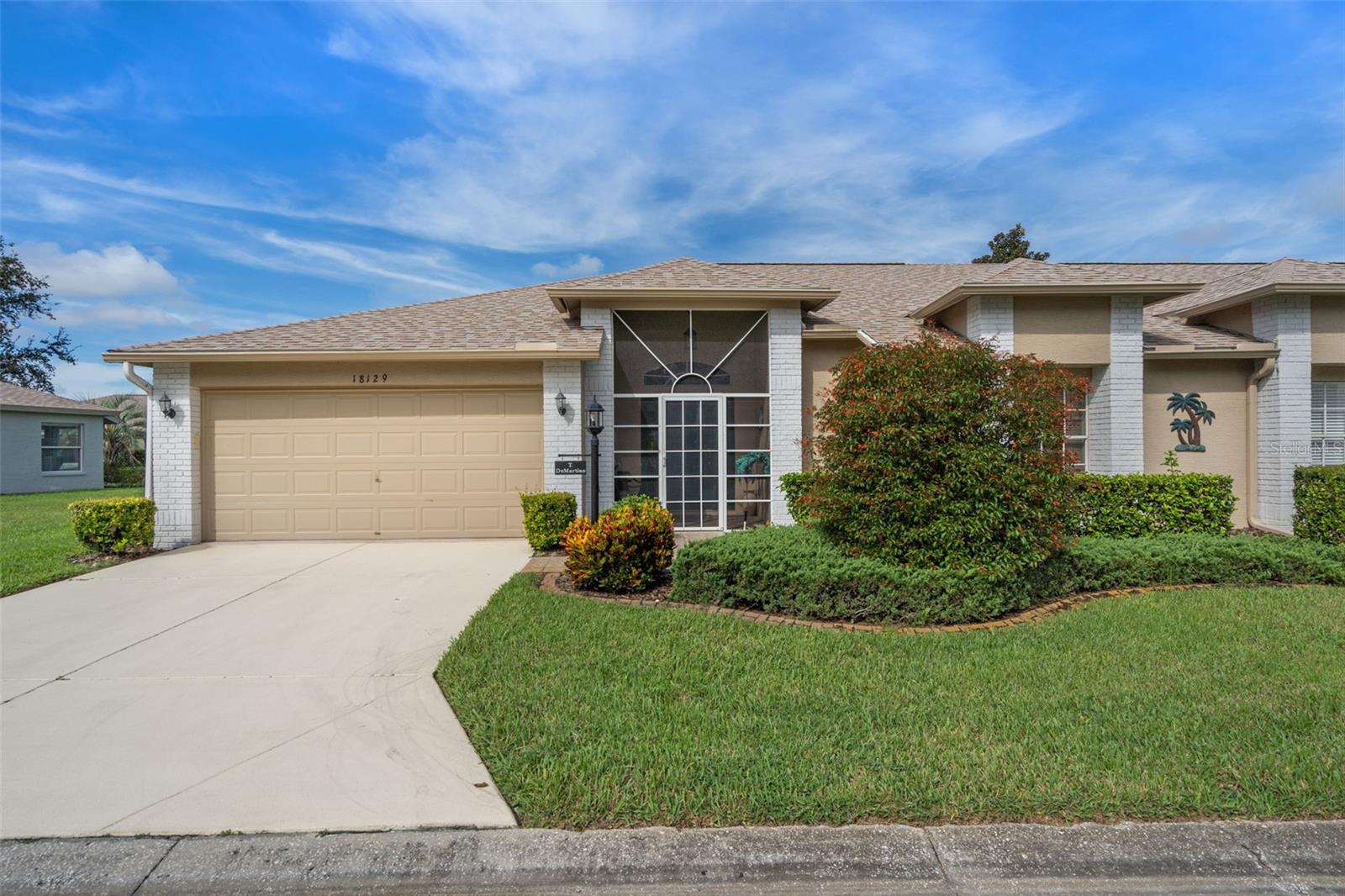 This end-unit Sea Breeze Villa nestled within Pine Meadow Village is a must-see, move-in ready home that has been meticulously maintained in pristine condition, with no prior pets or smoking. Enjoy refined elegance and a traditional ambience upon entry as the home is tastefully designed. A welcoming screened entry leads to a private front door and inviting foyer with a convenient coat closet. The open living and dining area is accented by a full wall of sliding glass doors, filling the space with natural light and creating a seamless connection to the enclosed and screened lanai. The bright kitchen, enhanced by an additional window only available in end units, showcases granite countertops, solid wood cabinetry, and modern finishes. The spacious primary suite offers his-and-hers walk-in closets and a private bath with dual sinks and a walk-in shower. The guest bedroom provides comfort with plush carpet and also a walk-in closet, while the guest bath features a tub and shower combination. An enclosed laundry room includes a utility sink, cabinets, and shelving for added storage. Additional upgrades include vaulted lace ceilings, custom drapery, gutters, water softener system, a 2024 roof, and a recently replaced hot water unit. A golf cart is also included with the sale. Situated within Heritage Pines, a premier 55+ gated golf community in Hudson, Florida, residents enjoy a private golf course, clubhouse with dining, resort-style pool, tennis courts, and a wide array of social clubs and activities. A new fitness center is also underway. This fully furnished 2-bedroom, 2-bath villa with approximately 1,686 square feet is located in Village 12, Pine Meadow Village, Flood Zone X, and is vacant and ready for immediate occupancy.