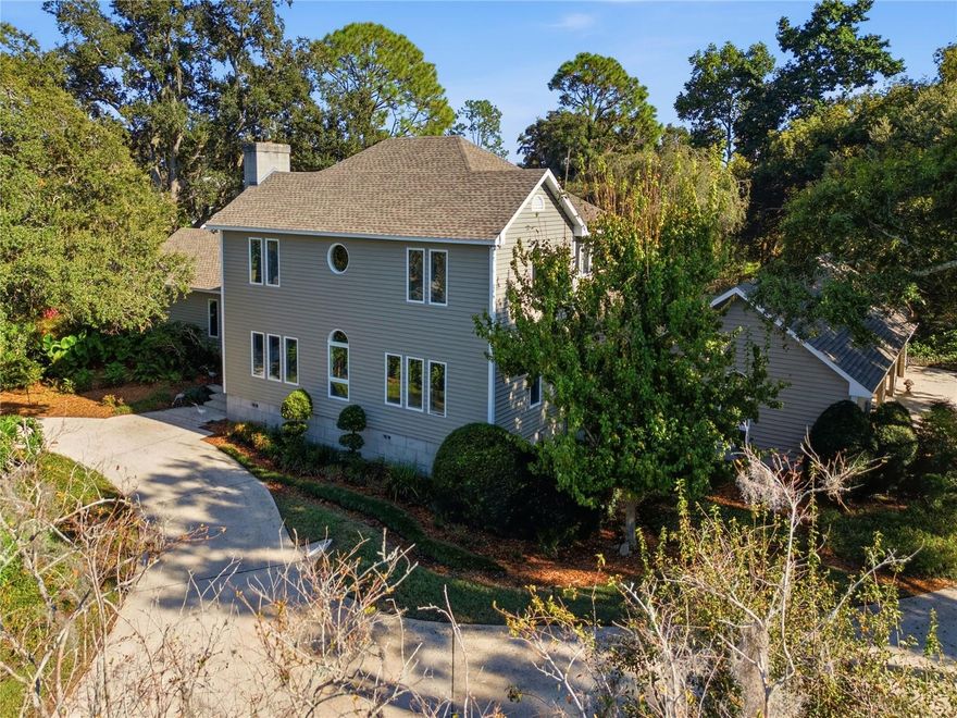 A custom blend of history, architecture, and contemporary warmth, 3 Brogden Court brings together contemporary simplicity, traditional influences, and Florida coastal ease—all in one unforgettable residence. Originally located near Downtown Winter Haven, the heart of the home was constructed in 1904 and carefully relocated to its current 1-acre setting and thoughtfully transformed into the distinctive, character-rich estate it is today. Offering 4 bedrooms, 2 full baths, 2 half baths, 3,918 sqft of living space, and over 5,000 sqft under roof, the home is tucked along a secluded drive with mature landscaping and a quiet street ideal for morning jogs, bike rides, or sunset strolls. The striking façade—framed by sweeping oaks, lush plantings, a circular drive, and hidden guest parking—sets the stage for the sun-drenched, curated interiors within. Warm hardwood floors, terracotta and mosaic tiles, carpeting in select areas, wood-lined ceilings, long sightlines, and thoughtfully placed windows fill the home with natural light. Architectural character is found throughout, including built-in shelving flanking the living room fireplace, detailed trim work, and hand-tooled banisters in the formal dining room. The formal living room captures serene views of the surrounding greenery, while the spacious family room—with Saltillo flooring and tongue-and-groove ceilings—embraces Florida’s indoor–outdoor lifestyle. The long, gallery-style kitchen offers clean-lined cabinetry, generous counters, transom windows, abundant storage, and a butler’s buffet with hidden understairs storage, making it perfect for those who love to cook and gather. The first-floor primary suite features multiple closets—including a walk-in—plus a dressing area, extended vanity, walk-in shower, and plumbing ready for a future soaking tub. An office and parlor complete the main level, while three guest bedrooms are privately positioned upstairs. Additional highlights include a large inside laundry room with separate storage room, an oversized three-car carport with attic storage, and an under-house crawlspace providing rare additional storage and easy access to components. This home naturally appeals to those who appreciate architecture, natural materials, clean lines, and curated spaces. Generous wall space, custom built-ins, and abundant natural light make it ideal for showcasing art, books, pottery, and handcrafted pieces. The quiet setting offers room to work, think, unwind, or entertain, while fans of contemporary and traditional design will love the warm woods and purposeful simplicity throughout. Snowbirds, second-home buyers, and long-term residents will value the home’s personality, craftsmanship, and enduring comfort—far from the standard Florida build. Set on a beautifully landscaped acre, the property feels peaceful and connected to nature—yet is minutes from outdoor recreation, golf, dining, shopping, and a vibrant downtown. Surrounded by 50 scenic lakes, including the renowned Winter Haven Chain of Lakes, residents enjoy watersports, lakeside dining, and unforgettable sunsets. With easy commutes to Tampa, Orlando, and major international airports, the convenience is unmatched. A rare offering of history, design, and architectural integrity—schedule your private tour today and experience the pinnacle of Florida luxury living at 3 Brogden Court.