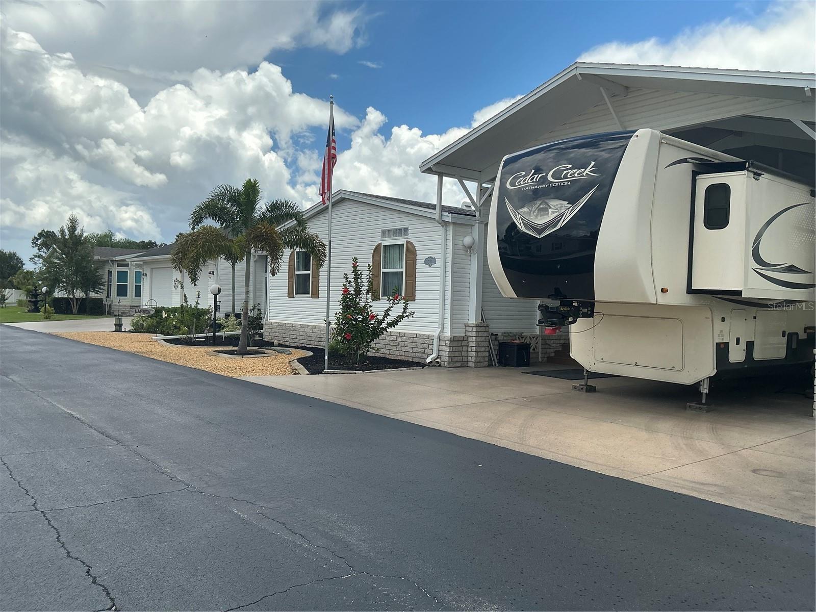 This home truly has it all! Attached RV port built to accommodate large RVs, with full hookups, golf cart shed w plenty of shelving for storage, upstairs is a large, air-conditioned bonus room that can be utilized as a man cave or craft room w separate storage area, ideal for seasonal decorations. This spacious home features an open floor plan, perfect for entertaining friends and family, whether a large gathering or enjoying a quiet evening, this home offers the ideal setting for both comfort & celebration. Step into the large screened-in entertaining area that's both fun & inviting, perfect spot for hosting unforgettable gatherings. This spacious outdoor retreat is thoughtfully decorated w festive lighting & cheerful accents that create a relaxed & welcoming vibe, plus a covered area for grilling just outside the screened area. This beautifully renovated home features a completely updated kitchen and both bathrooms. Enjoy brand-new cabinets, sinks, faucets, countertops and flooring throughout. A comfortable lanai is located just off the kitchen, offering the perfect spot to relax, with convenient access to the RV port through a separate exit. The oversized two-car garage features automatic openers for both doors and extra storage in the loft, accessible by a full staircase and a convenient lift for hauling items. It also includes a separate room w a toilet, laundry tub with on demand water heater and a side-by-side refrigerator. This is truly a must-see-home to fully appreciate everything it has to offer.
This home is located in central Florida, in a 55+ resident owned, gated community where you own your property, no lot rent! From the time you enter the front gates you can see the pride of ownership! The association fee is $293.50 per month, collected twice a year, includes lawn mowed & trimmed, removal of garbage for the community, cable & internet. There's a nine-hole executive golf course in the park that's a separate business, so all fees are separate. This is an active, friendly community so you have the ease of meeting new friends. Take the time to come see what all this home & community has to offer, I'd love to show you around!