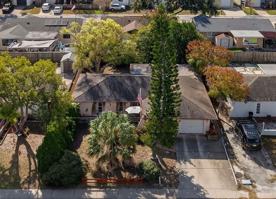 Whether you’re looking for a primary residence, seasonal home, or investment opportunity, this property presents an excellent opportunity to add significant value through updating this well-kept solid block home. The spacious lot is high and dry and offers a fully fenced private back yard. On arrival you will immediately notice the curb appeal provided by the home’s great lines, hip roof, mature ornamental trees and pleasing front patio.  Step inside through the hardwood front door and experience the welcoming atmosphere of the open-plan living spaces. The living room connects seamlessly to the dining area, the kitchen, and a family room at the back of the house currently used as an office/den. From the dining room, sliders open out to the Florida room from where you access the fully fenced private back yard. Both generous bedrooms feature walk in closets!  The oversized garage is 21x18 or 378ft².  Looking at this from a potential remodeling perspective, it’s worth noting that you would not need to move any walls as the layout is already in a pleasing open plan, there are no popcorn ceilings, and the carpeted flooring, while in good shape, could be easily updated in a snap.  The roof was replaced in 2011, and the central HVAC was done in 2020.  The home is located on a quiet street just 2 minutes from Publix and CVS, 5 minutes from Walmart, 10 minutes from a selection of great waterfront restaurants, many other stores and restaurants and it is ~37 minutes from Tampa International Airport.