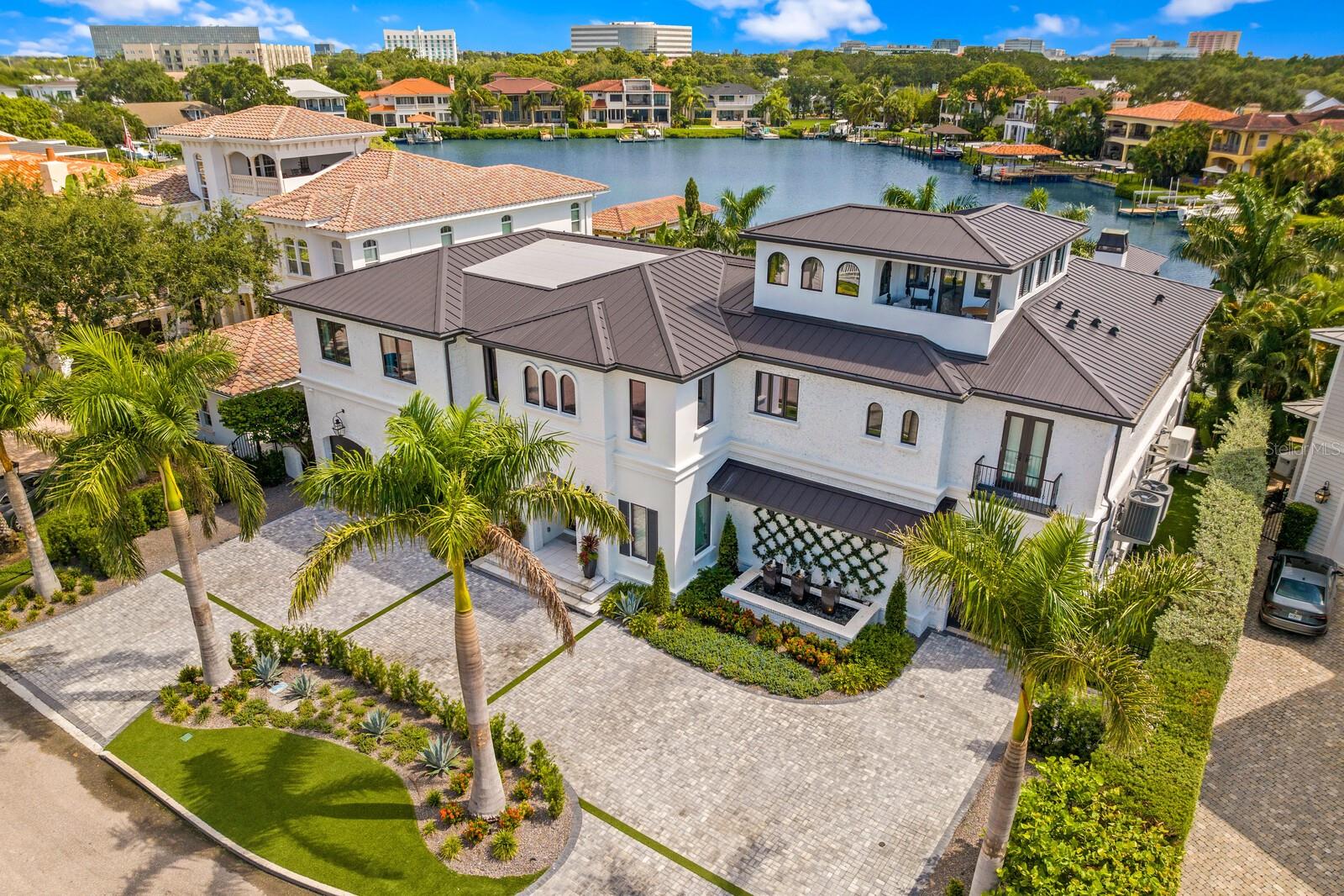 Exquisite Beach Park Waterfront Estate – A Masterpiece of Modern Elegance and Sophisticated Luxury. Meticulously designed, masterfully rebuilt and completely renovated LIKE NEW waterfront mansion offering state-of-the-art construction (2024) and opulent finishes for a coveted South Tampa waterfront lifestyle. Striking European-inspired design, an oversized circular drive, and custom arched glass front door welcome you to this oasis on the protected deep-water “Pirate’s Cove.” Boasting sweeping water views, nearly 7,000 SF of refined living spaces, 6 Bedrooms, 6.5 Baths and 3+ Car Garages. Offering exquisite details and bespoke finishes, this is more than a home; it’s a statement of modern elegance. A dramatic marble foyer opens to the dining room with Pecky Cypress beams, and superior chef’s kitchen for upscale entertaining. The kitchen features dual marble waterfall islands, Sub-Zero appliances, walk-in pantry, beverage/wine bars, and a seamless pass-through window to the outdoor waterfront entertainment area. The first level flows into an inviting living room anchored by a sleek gas fireplace and retracting EuroWall sliding doors to the backyard oasis, along with a private guest suite, pool bath, and spa-like cabana room gym. The second level features five ensuite bedrooms with marble bathrooms, an oversized laundry room with dual washers/dryers, elevator, an additional loft area with beverage bar, large terrace overlooking the water, and a state-of-the-art theatre. Immerse yourself in a cinematic experience with surround sound, starlight ceiling, and layered seating. Ascend the custom-steel and glass staircase to the private third-level office featuring a covered terrace and amazing 360-degree water views where you can enjoy stunning open-water sunsets. The primary suite is an elegant experience with foyer entry, full retracting glass doors to a waterfront terrace and linear fireplace overlooking the pool, relaxed sitting area, automated window panels, designer closet, and lavish bath with heated marble floor and appointments worthy of the very best five-star resorts. Refined living continues outdoors to the expansive loggia, with Pecky cypress ceiling, linear fire features, heated knife-edge pool, infinity-edge spa, and a private dock overlooking the coveted deep-water Cove, perfect for access directly to the open water, or observing the dolphin and manatee from your back yard. Enjoy alfresco dining, entertain large gatherings, or unwind in the seating areas with automated screens, surrounded by meticulous resort-style landscaping. Featuring sunset views of Tampa Bay and sunrises over Pirates Cove, this enclave of fewer than 20 luxury homes provide a decadent waterfront lifestyle. Enjoy direct access to Tampa Bay with a 40’ covered boat lift with 30,000 lb lift and additional slip. Thoughtful luxury design features throughout include white oak flooring with brass and marble inlays, automated Lutron shades and elegant window panels, designer wallpaper, bronze mirrors, glass panel and spiral stairways, custom closet systems, and water views from every room. Innovative technology provides efficiency and comfort with Control4 home automation, security cameras, whole home generator, new impact doors/windows/roofing, new plumbing/electric/HVAC systems, and whole home water filtration. Situated on a cul-de-sac with Charleston-inspired streetlamps and no visible overhead powerlines.