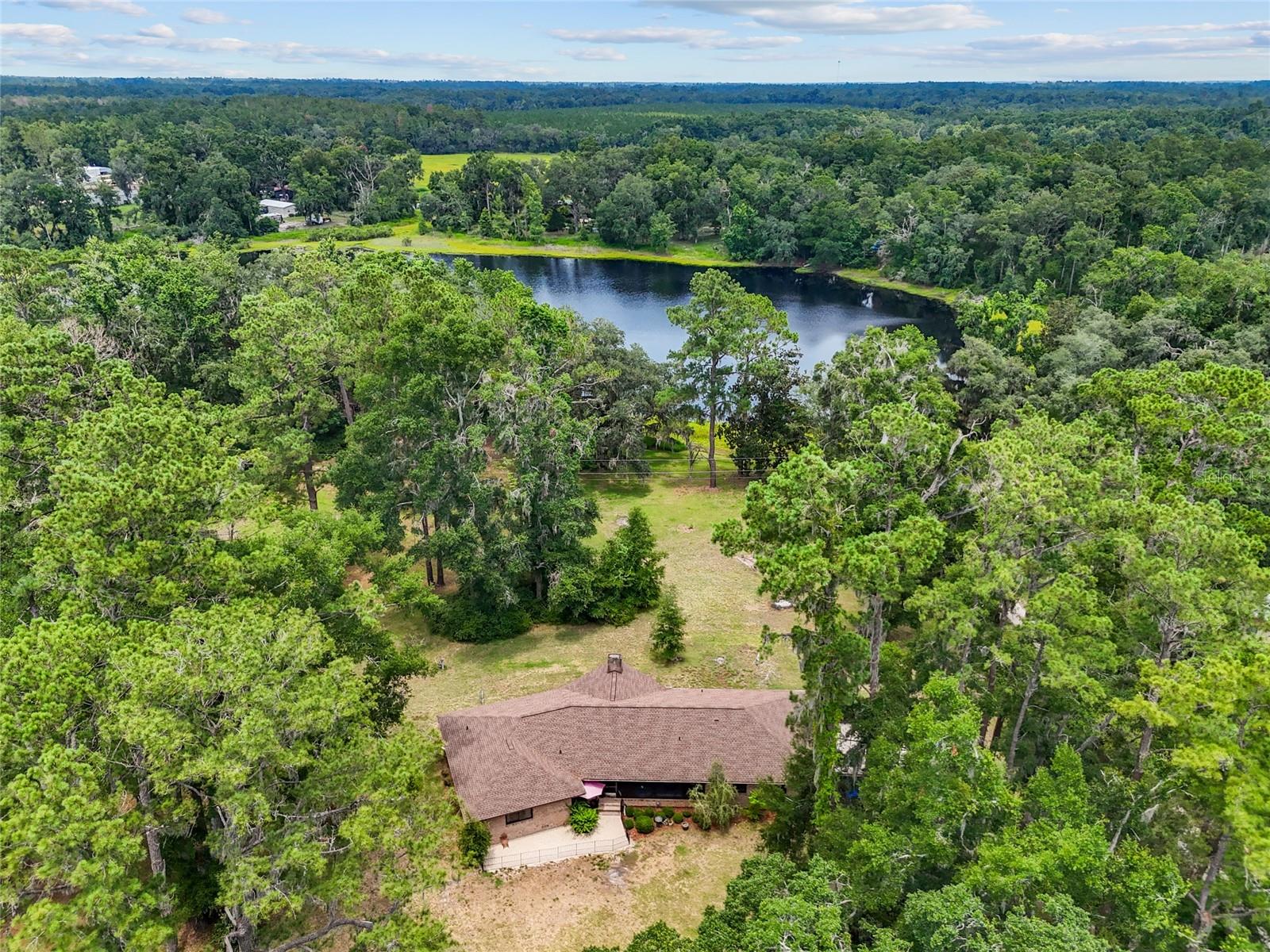 Looking for a home with lake front acreage? You found it! This solid brick construction home is situated on a gorgeous 12+ acre lot, surrounded by century old oaks, and overlooking a private lake- old Florida living doesn’t get better than this. Featuring 3 bedrooms, 2.5 bathrooms, a spacious living room with lake views, a screened in porch and garage, an attached 2 car garage, a 2 car carport, and an additional detached oversized 1 car garage- there is no shortage of storage for all of your toys. The kitchen features stainless steel appliances, and the entire home features upgraded vinyl plank flooring- no carpet! Even better, the roof, windows, and hot water heater have all been replaced since 2023! You won’t find a nicer home on 10+ acres at this price. Conveniently located within 10 minutes of Publix, Lowes, Walmart, and Tractor Supply. Don’t miss out!