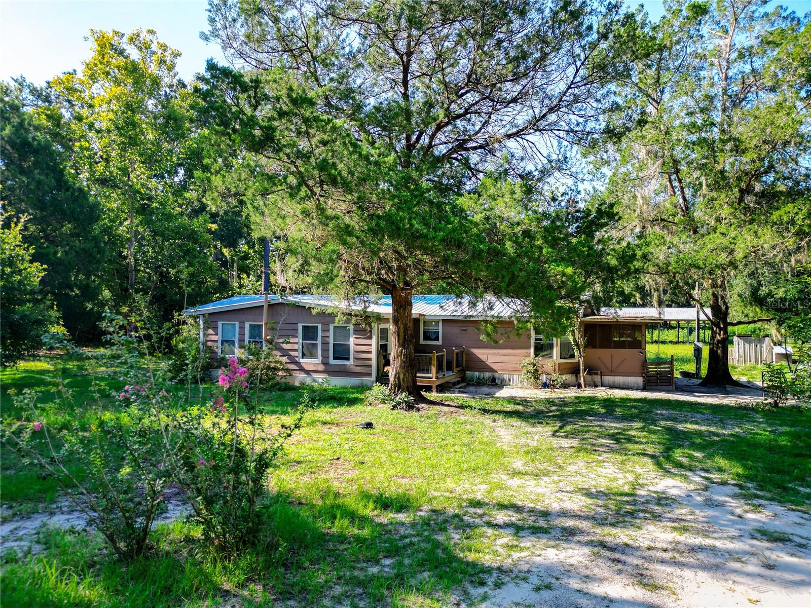 AMAZING OPPORTUNITY IN THIS PRIVATE 9.8-acre FARM! Backing up to the state forest, it offers all the peace and natural beauty you’ve been looking for. The 3-bedroom, 2-bath home (about 2,000 sq ft) includes two comfy living rooms, a fireplace, wood-burning stove, a big dining area, and a spacious kitchen with an eat-in bar—plenty of room to spread out. Step outside and you’ll find a shooting range, a 24x40 pole barn, and a massive fire pit perfect for hanging out with friends and family. The land is full of character, with magnolias, cedar trees, bamboo, and more. The home also features a metal roof, screened-in mudroom, and a custom front porch to enjoy the views. You’ve got propane cooking, central A/C, and plank flooring for everyday comfort. Conveniently located near Bronson and Williston, and not far from Ocala or Gainesville. Whether you're into hobby farming, outdoor fun, or just want some breathing room, this place has you covered. There’s no HOA, taxes are low, and the home’s move-in ready. Make it yours—come see what peaceful country living in Levy County feels like!
