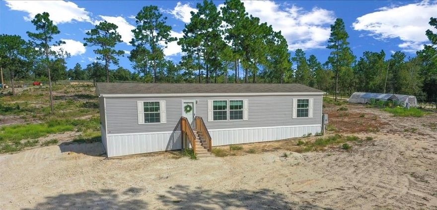 Live the mini-farm life you’ve been dreaming of in this 2024 double-wide manufactured home offering 3 bedrooms, 2 baths and 1,494 sqft of living space, all set on 5 fully fenced acres. Perfectly located for equestrians and outdoor enthusiasts, you’ll be just 22-miles from the World Equestrian Center in Ocala, 4.1-miles from Goethe State Forest with hundreds of miles of riding trails and 17-miles from HITS. The zoning allows for horses, goats, chickens, pigs and more—giving you the freedom to create the farm you’ve always envisioned.
Inside the home welcomes you with an open floor plan filled with natural light, highlighted by low-maintenance linoleum flooring throughout. The kitchen boasts ample cabinet & counter space, a center cooking island and room to gather, while the spacious primary suite features a walk-in closet and en suite bathroom with a walk-in shower. A split bedroom plan ensures privacy with two additional generously sized bedrooms—each with its own walk-in closet—conveniently located near the guest bath. The property itself is a blank slate ready for your vision—whether that’s adding a barn, pastures or starting a garden the possibilities are endless Already in place are a variety of established plantings including fig, avocado, yuca, corn, lemongrass and banana trees. With plenty of room for animals, equipment and outdoor living, this property provides endless possibilities. Enjoy the peaceful lifestyle of country living while still being close to world-class equestrian facilities, endless trails and modern conveniences. Schedule your Private showing today!