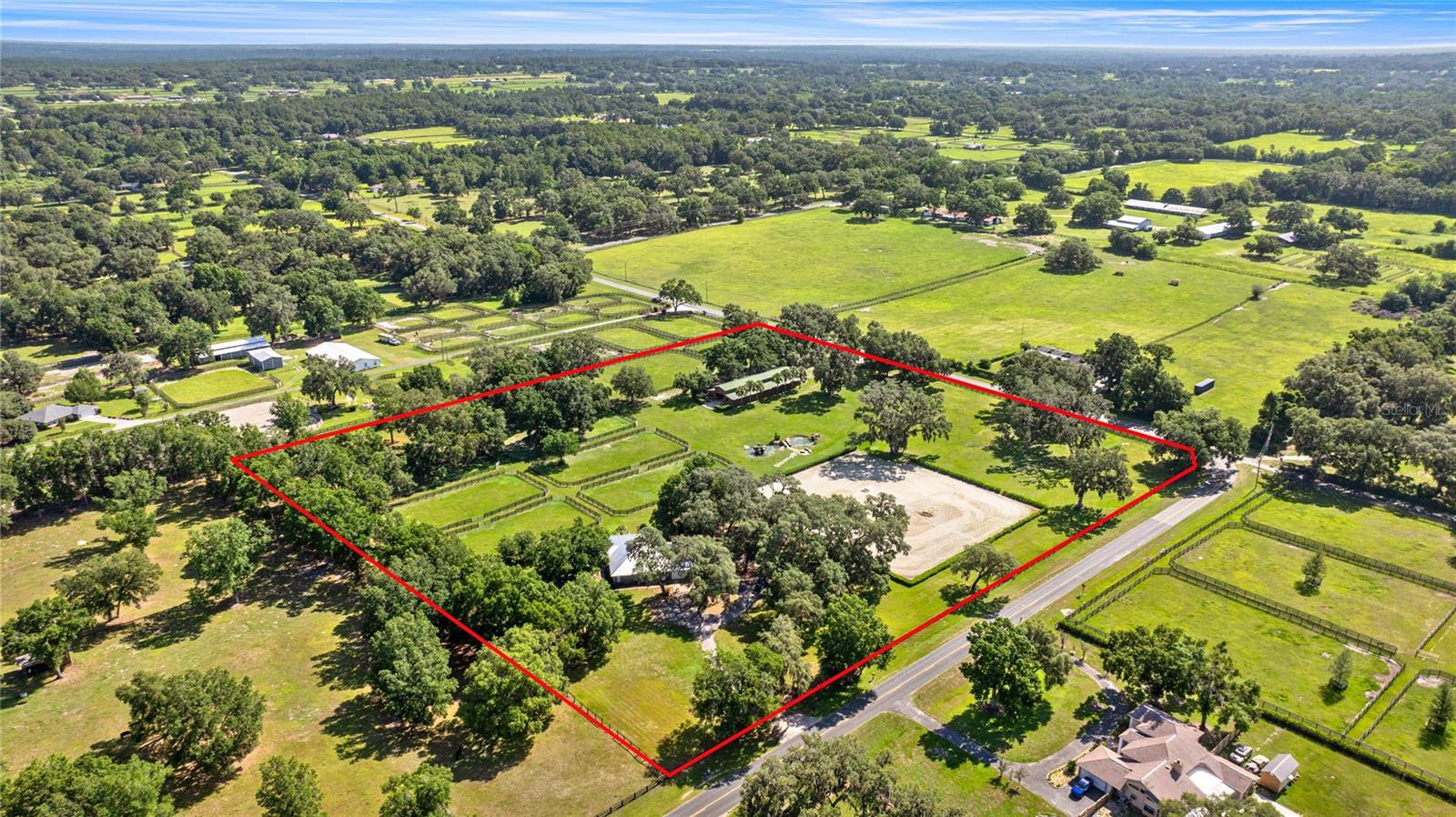 Discover a meticulously designed, turn-key 10-acre Hunter/Jumper estate, perfectly situated just 4 miles from HITS and 4 miles from the World Equestrian Center. (WEC). This exceptional property caters to hobbyists, amateurs, and professionals alike, offering unparalleled functionality for seasonal or year-round equestrians. The main residence features 3-bedroom, 2-bath plus an office. With modern elegance such as concrete floors, open-concept layout and spacious primary suite with a spa like bathroom equipped with soaking tub and shower. Other notable features include a large office ideal for managing your equestrian business. Kitchen has all stainless appliances and both a dinning room and break nook for perfect flow. Laundry room with washer and dryer lead off to the 2-car garage. The property is equipped with a diesel generator, and a circular driveway with ample parking 2 (two) private gates ensuring seclusion from home and barn life. Enjoy outdoor living with beautifully landscaped grounds.
The equestrian facilities are second to none. 14-stall center-aisle barn, accessible via its own gated entrance, boasts 2 wash racks one with hot and cold water, a grooming area, a office/barn apartment with a full ensuite bathroom, a tack/laundry room, and 1/2 bath. In addition 3 RV hookups with well and septic. Nine meticulously maintained paddocks with 4-board fencing are separated by 12’-16’ lanes, ensuring ease of access and safety. 200’x200’ irrigated GGT arena, complete with French drains and a crushed concrete base, is complemented by a large grass riding field featuring a bank complex with a stone wall. A picturesque pond, adorned with two fountains, a firepit, and a stone bridge, adds charm to the landscape. Additional amenities include a trailer parking area and thoughtfully designed infrastructure to support a seamless operation and storage shed for hay or equipment storage. This estate is a must-see for discerning equestrians seeking a blend of luxury, practicality, and proximity to Ocala’s world-class equestrian venues. Schedule your private tour today to experience this extraordinary property firsthand.