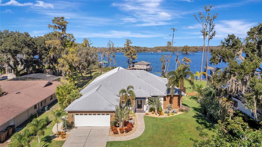 Discover an exceptional lakefront luxury residence on the shores of Lake Minnehaha, part of the prestigious Clermont Chain of Lakes. This custom-built four-bedroom, three-and-a-half-bath home has been completely remodeled with meticulous attention to detail, offering nearly 3,000 square feet of refined living space and an extraordinary 1,000-square-foot lakefront porch designed for effortless entertaining and relaxation. A major renovation completed in 2021 by Terrell Construction elevated the home to a true coastal modern masterpiece. The interior showcases a custom-designed kitchen with Cambria quartz surfaces, Fisher & Paykel induction oven and double dishwasher, coffered ceilings, elegant porcelain wood plank tile flooring, and thoughtfully curated fixtures and fans. The expanded living and dining spaces feature a striking custom-built entertainment wall with an electric heated fireplace, perfectly blending warmth and contemporary design. The owner’s suite offers serene lake views, and a beautifully updated bath with dual sinks, walk in shower with double shower heads and free standing modern tub, while the two interior guest bathrooms were enhanced in 2025 for a fresh, cohesive aesthetic. Additional interior comforts include a custom designed mudroom, laundry room, whole-house replumb, spray foam insulation, dual hot water heaters, Alexa-integrated lighting in key living areas, triple PGT sliders and an efficient three-zone HVAC system. Equally impressive, the exterior has been extensively updated to elevate both style and durability. Recent enhancements include new PGT front windows, Bahama shutters, NewTech wood accent walls, fresh Sherwin-Williams exterior paint, revitalized landscaping with new sod, and a new privacy fence with stem wall. The lighted paver walkway, epoxy-finished garage floor, Plug for RV/Generator or Tesla charger, and lake-sourced irrigation further emphasize the home’s thoughtful design and functionality. A durable metal roof installed in 2015 and updated structural features reinforce long-term peace of mind. The expansive lakefront back porch—added during the 2021 remodel—serves as the ultimate outdoor sanctuary, complete with an outdoor kitchen, automatic screens, outdoor shower, and a dedicated pool half-bath, creating a seamless transition between indoor and outdoor living. Just beyond, a heated electric saltwater pool overlooks the sparkling water, while a grandfathered in boathouse with dock and lift provides private access to one of Central Florida’s most coveted lake chains. The property is situated behind a concrete seawall and offers breathtaking views from sunrise to sunset. With no HOA, the home affords an exceptional degree of privacy and freedom rarely found among luxury lakefront properties. Exquisite craftsmanship, timeless finishes, and a premier lakefront setting come together to offer an unparalleled lifestyle. This meticulously reimagined home sets a new standard for luxury lakefront living, delivering an exceptional blend of elegance, comfort, and premier Clermont waterfront views. Perfectly situated just moments from Highway 50 and Highway 27, and minutes from downtown Clermont, premier hospitals, schools, shopping, and dining, this distinguished lakefront home offers unrivaled convenience while remaining only 40 minutes from Disney World and Orlando International Airport—an extraordinary blend of luxury living and unbeatable location.