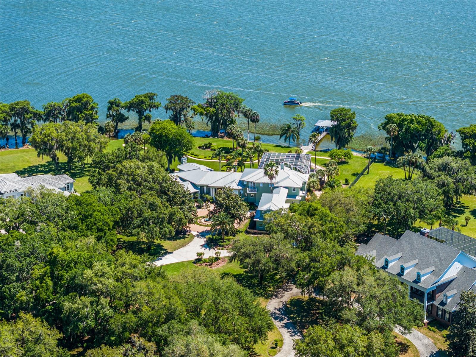 Discover an unrivaled waterfront paradise nestled directly on the shores of Lake Harris, part of the esteemed Harris Chain of Lakes. This expansive estate, accessible through a private gated driveway, offers a unique fusion of privacy, luxury, and leisure. The immediate homesite consists of 3.06 acres, while enjoying private ownership of an adjacent 46+/- conservation acres for additional privacy.
Step into the custom-built 8,542 square foot sanctuary, masterfully designed to showcase breathtaking lake views from virtually every room. Marvel at the exquisite craftsmanship and attention to detail, from the elegantly laid diagonal hardwood floors and porcelain tiles to the intricate ceilings showcasing tongue & groove, barrel, coffered, and tray designs.
Delight in the custom millwork, leaded glass entry door, granite countertops, multiple fireplaces, and designer finishes that grace every corner. Oversized windows throughout invite an abundance of natural light, framing the tranquil water vistas.
Embrace the epitome of outdoor living that caters to both relaxation as well as formal entertaining. Your private backyard oasis awaits, complete with a serene walking path leading down to your personal firepit area and composite dock and boathouse, equipped with two lifts. Indoors, the thoughtfully designed floorplan offers a myriad of living spaces for everyone to enjoy. The open chef’s kitchen and dining areas provide the perfect setting for hosting unforgettable gatherings, seamlessly flowing into the massive pool area. Discover additional living spaces, including a dedicated homework station, a first-floor game room, and an office boasting custom wood details. Each bedroom hosts its own luxurious ensuite, while the versatile room above the garage can be transformed from a movie theater to guest quarters, home gym, or any flex space desired.
Nestled within the renowned Harris Chain of Lakes in Central Florida, this exclusive retreat offers an unparalleled sense of seclusion while remaining mere minutes from a wealth of amenities including access to a public dock and boat ramp for additional ease. Explore the charming downtowns of Leesburg and nearby Mount Dora. Immerse yourself in the vibrant atmosphere of The Villages, and enjoy convenient access to UF Health & Advent Health, golf courses, and sports complexes. A myriad of shopping and dining options along US Hwy 441 await, and Leesburg International Airport is just a short drive away. Disney and Orlando International Airport are both within an hour's reach, making this estate the epitome of tranquility and convenience.