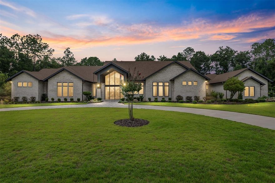 Discover a rare opportunity to own an architectural masterpiece nestled on 1.97 lush acres in one of the area’s most prestigious gated communities. This stunning 6,238 sq ft custom estate seamlessly blends sophisticated design, exceptional craftsmanship, and resort-style amenities—offering a lifestyle of comfort, elegance, and ease.

Step through expansive glass doors into a world of refined beauty. The grand living room impresses with a bespoke wood ceiling, accent brick wall, designer fireplace, and accordion-style glass doors that invite seamless indoor-outdoor living. The chef-inspired kitchen is a true showpiece, featuring exquisite blue and gold cabinetry, Waterstone fixtures, a gas cooktop, built-in refrigerator, and an expansive butler’s pantry fully equipped with top-tier appliances.

The adjacent dining room is equally stunning, adorned with a brick accent wall, Restoration Hardware lighting, and soaring ceilings that flood the space with natural light.

Thoughtful design touches abound throughout—from a stylish stop-and-drop zone with Elkay bottle filling station and brick details, to an oversized laundry room outfitted with custom cabinetry and dual washers and dryers. Pet lovers will appreciate the dedicated dog room, complete with built-in storage and a custom dog wash station.

The private office features beam ceilings and a built-in closet, while the ultimate “man cave” showcases a custom Batman door and fully built-in cabinetry. The luxurious primary suite is a serene retreat with its own custom wood ceiling and direct access to a private gym equipped with cabinetry and a beverage fridge. Dual walk-in closets offer high-end organizational systems, and the spa-inspired bath stuns with floating cabinetry, a sculptural concrete soaking tub, oversized shower, and Toto bidet toilet.

The detached guest house offers a full bath, built-ins with sink, and connects to a spacious storage area with extensive shelving.

Step outside to your own private resort—an entertainer’s paradise featuring a covered lanai with wood-paneled ceiling, brick fireplace, outdoor kitchen with pizza oven, refrigerator, ice maker, remote-controlled screens, and a heated pool and spa. For the active lifestyle, enjoy your own private tennis court and a dedicated structure housing a 1,000-gallon whole-house water purification system.

This one-of-a-kind estate delivers timeless luxury, unparalleled comfort, and an extraordinary lifestyle in a tranquil, secure setting.