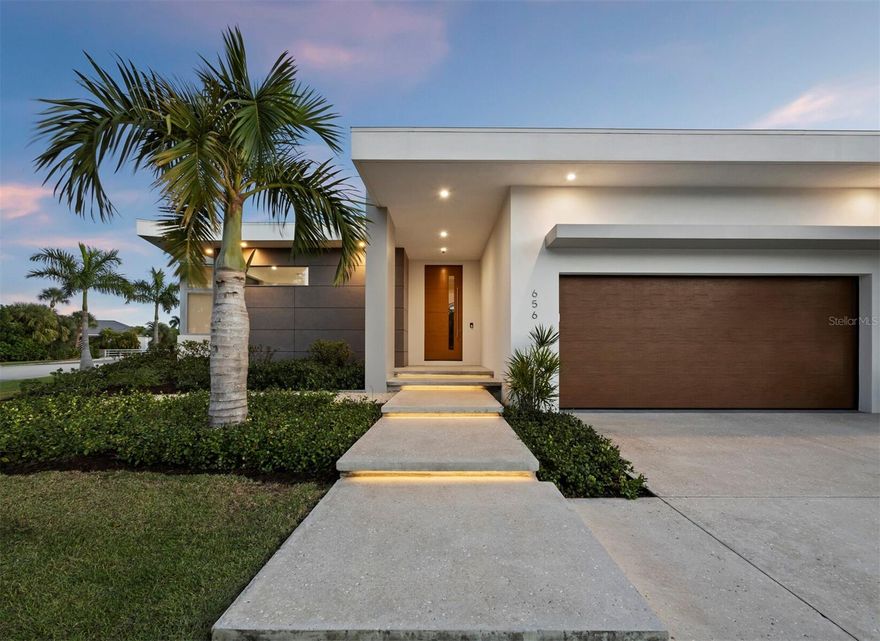 A showcase of architecture and radiant light, this 3BR + Den/3.5BA residence commands a beautifully landscaped extended corner lot on one of Bird Key’s premier canal-front properties. The 2023 Murray built home boasts crisp lines, expanses of glass and warm wood accents that signal the home’s elevated contemporary character. Step inside and the design intention becomes unmistakable, as skylights, clerestory windows and full-height sliders flood every room with natural light and create a sense of openness that feels both artful and effortless. The kitchen is a striking focal point, styled with low-profile cabinetry, stone surfaces, top-tier stainless-steel appliances and a gas range. A large breakfast bar connects seamlessly to the dining and living areas, while a back-kitchen area keeps the main space sleek and uncluttered. The living room is a bright retreat anchored by a custom accent wall with a gas fireplace and wrapped in soaring windows and glass doors. The primary suite offers a spacious, quiet refuge with pool access, a custom walk-in closet and a stunning modern bath with floating dual vanities, freestanding tub, separate water closet and an open shower. Sliding glass doors lead to the pool terrace, where covered sitting areas with roll-down hurricane-rated screens, a full summer kitchen, expansive paver deck and open pool create an inviting outdoor living environment. The canal-front setting provides exceptional boating water, quick access to the bay and a large dock with 16,000 LB boat lift - 158' seawall. This amenity rich home also features a whole-home generator, irrigation well for landscaping, oversize garage perfect for car lifts, and water purification system.
