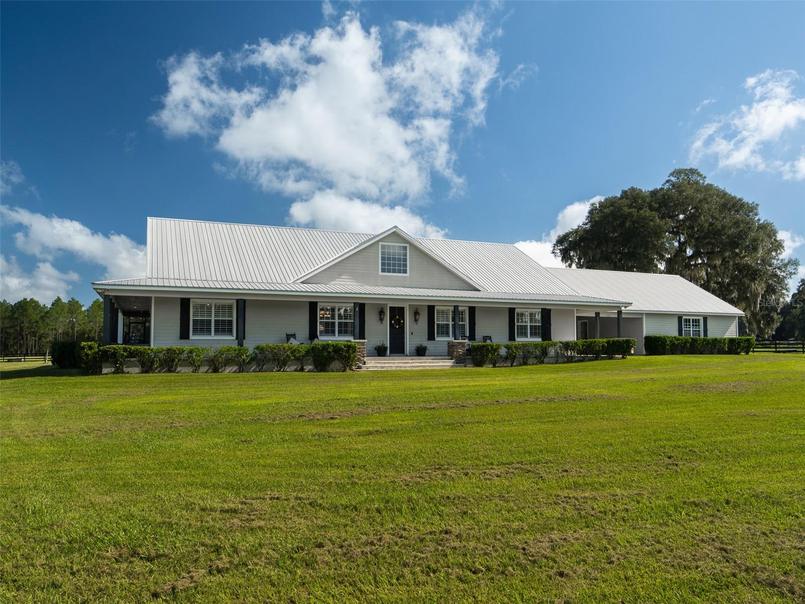 Nestled in NW Ocala, just 15 minutes from the World Equestrian Center and 5 minutes from HITS, this fully fenced 22+ acre property offers a perfect blend of equestrian excellence and peaceful country living! Dotted with mature oak trees and designed for functionality and beauty, the land features four lush paddocks that provide ample space for turnout and training. A well-equipped 6-stall barn with a spacious foaling stall and dedicated tack and feed rooms ensures your horses are cared for. The charming 3-bedroom, 2 full and 3 half-bath residence welcomes you with a classic wrap-around porch and warm, inviting interiors. Inside, a cozy kitchen flows effortlessly into the main living areas, making it ideal for everyday living and entertaining. Tray ceilings add architectural interest, while a beautiful stone fireplace serves as the heart of the home, perfect for relaxing evenings. French doors open to a covered back porch, leading to a screened-in outdoor living area that showcases a sparkling in-ground pool and spa, your own private retreat after a day in the saddle. This exceptional property is a true sanctuary in one of Ocala’s most sought-after locations. Whether you're a competitive rider or simply seeking the serenity of country life, this estate is ready to welcome you home.