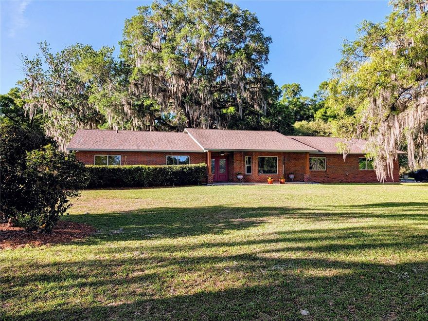 Country Comfort in High Springs: This exceptional property offers a rare combination of natural beauty, privacy in relation to neighboring homes, and convenience to the amenities and necessities families need. Retreat to nature at the end of a private lane where the gated entry leads to 9.77 park-like acres. Ancient live oaks impress with their spreading limbs and towering canopies, remnants of the forest which existed here centuries ago. Old-growth magnolias, dogwood, chestnut and cedars add to the variety of trees and shrubs which create a pleasant scene soothing to the eye and to the soul. The front of the home faces the back of the property rather than the entry drive, affording a view north across open pasture ideal for a horse or two. The horse shed is ready for a new occupant. The current owners enjoyed sitting in rockers on the porch in the evenings watching the resident deer come out to graze. Common each year are twin fawns. Wild turkeys are daily visitors as well, the gobblers displaying their fanned out tail feathers in the spring mating season. Neighboring homes are well away and not seen from the home, offering exceptional privacy. Much is made in real estate sales of location in a home's value, and this location adds considerable value to this home. From the property entry gate, the distance to County Road (CR) 236 is 0.2 mi. At CR 236 one can turn right and to 2.2 miles to downtown High Springs, or one can turn left and go 2.2 miles to I-75 exit 404 (High Springs/Lake Butler) where Gainesville is 25 miles to the south and Lake City is 25 miles to the north. Convenience of location doesn't get any better than that! What one needs for daily living is a five minute drive away, but to be at this home it's as if the busy world doesn't exist. Recent updates include: Roof shingles (high-quality 3-dimensional) were replaced 5 years ago; all the windows are new; the front entry doors are new and are high-impact rated as is the newer garage door; the water heater and water softener are new; all the sinks and toilets have been replaced; the kitchen appliances are newer; the dining and living room flooring is vinyl plank flooring installed in 2019; the bedroom carpets were replaced in 2017. The roof and the house exterior were soft pressure-washed recently. There are 2 HVAC units, one for the bedroom section and one for the main house. There are 2 septic systems, one for the kitchen and one for the bathrooms. Built in 1981, the house is all brick. Here one can retreat from it all while enjoying the convenience of quick access to just about anything one would need.