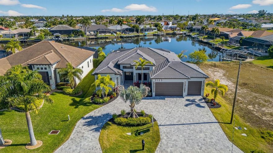 One or more photo(s) has been virtually staged. Experience the ultimate blend of luxury, comfort, and modern coastal design in this newly completed 3-bedroom + den, 3-bathroom waterfront residence with a spacious 3-car garage. Offering 2,200 square feet of thoughtfully designed living space, this exceptional home is ideally located just off Surfside Blvd in one of Cape Coral’s desirable neighborhoods, with Gulf access on an impressive 350-foot-wide canal.
From the moment you step inside, soaring ceilings, refined finishes, and a bright open-concept layout create an atmosphere of elegance and sophistication. The gourmet kitchen is a true showpiece, featuring a quartz waterfall island with bar seating, premium appliances, sleek backsplash, and a custom coffee station—perfect for everyday living and effortless entertaining.

The living area is anchored by a striking custom media wall complete with an 85” TV and electric fireplace, complemented by dramatic 12-foot coffered ceilings that elevate the space while maintaining a warm, inviting feel.
The owner’s suite serves as a private retreat, offering direct lanai access, dual oversized walk-in closets, floating vanities, a freestanding soaking tub with designer accent backsplash, and a beautifully appointed walk-in shower—designed to rival a luxury spa experience.
Step outside to embrace true Florida waterfront living. The expansive covered lanai overlooks a heated pool and spa and features an outdoor grill station, dedicated seating area with mounted TV, and ample space for hosting guests, enjoying sunset views, or unwinding in your own private oasis year-round.

Equally impressive, the exterior showcases a semi-circular paver driveway, lush tropical landscaping, and a modern tile roof that blends durability with timeless architectural appeal. Fully completed and move-in ready for its very first owner.

If you’re seeking a luxury Gulf-access home that delivers on design, location, and lifestyle—without compromise—this property truly stands apart. Schedule your private showing today and experience Cape Coral waterfront living at its finest.