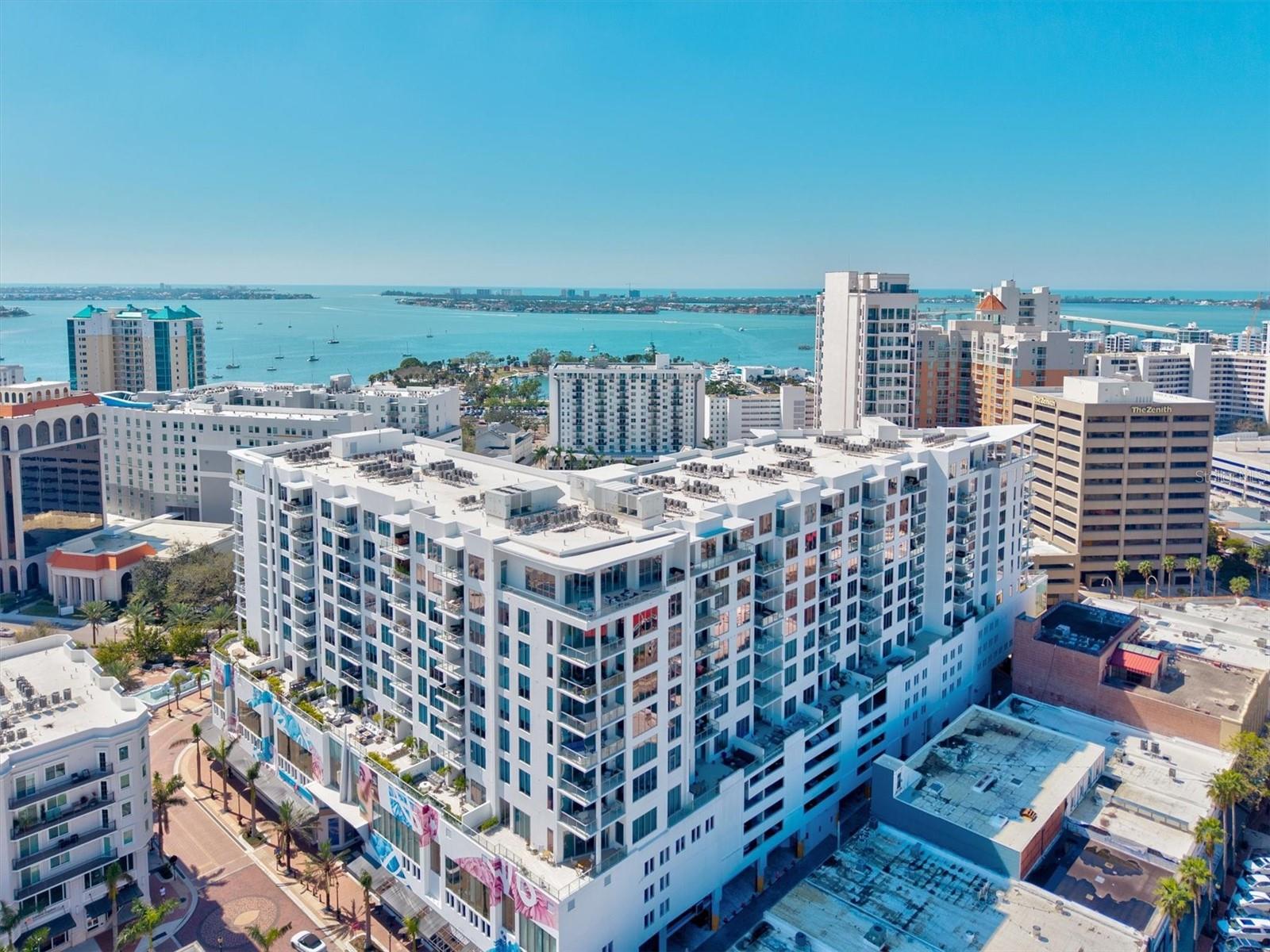 Located on the seventh floor of the MARK SARASOTA, this modern downtown residence offers expansive views of the lushly landscaped amenity deck and delivers a seamless blend of comfort and sophistication. This two-bedroom, two-and-a-half-bath home features an additional office or den and boasts an open layout ideal for both relaxation and entertaining. Premium upgrades include powered window shades and custom closet systems throughout the home.
The gourmet kitchen showcases quartz countertops, white gloss cabinetry with under-cabinet lighting, and a suite of JennAir appliances. Porcelain plank tile flooring extends throughout the main living areas and bedrooms for a cohesive design.
Engineered to Miami-Dade Category 5 construction standards, the building features impact-rated windows and post-tension concrete construction, providing added peace of mind.
Mark Sarasota is renowned for having one of the most extensive amenity offerings in the region, including a resort-style elevated pool and spa, private cabanas, a fire pit, and grilling stations. A state-of-the-art fitness center, Club Room with catering kitchen and bar, and a News Room for coffee and conversation provide year-round lifestyle opportunities. A robust social committee curates a variety of monthly events and activities, fostering a vibrant resident community.
This residence features one secured garage parking space, on-floor private storage, and a pet-friendly policy that allows two pets. Secure, access-controlled lobbies and elevators, along with a 24-hour concierge, complete this unparalleled downtown offering. The Mark’s location places residents within half a mile of Bayfront Park, Marina Jack, Selby Gardens, and the city’s top dining and cultural venues.