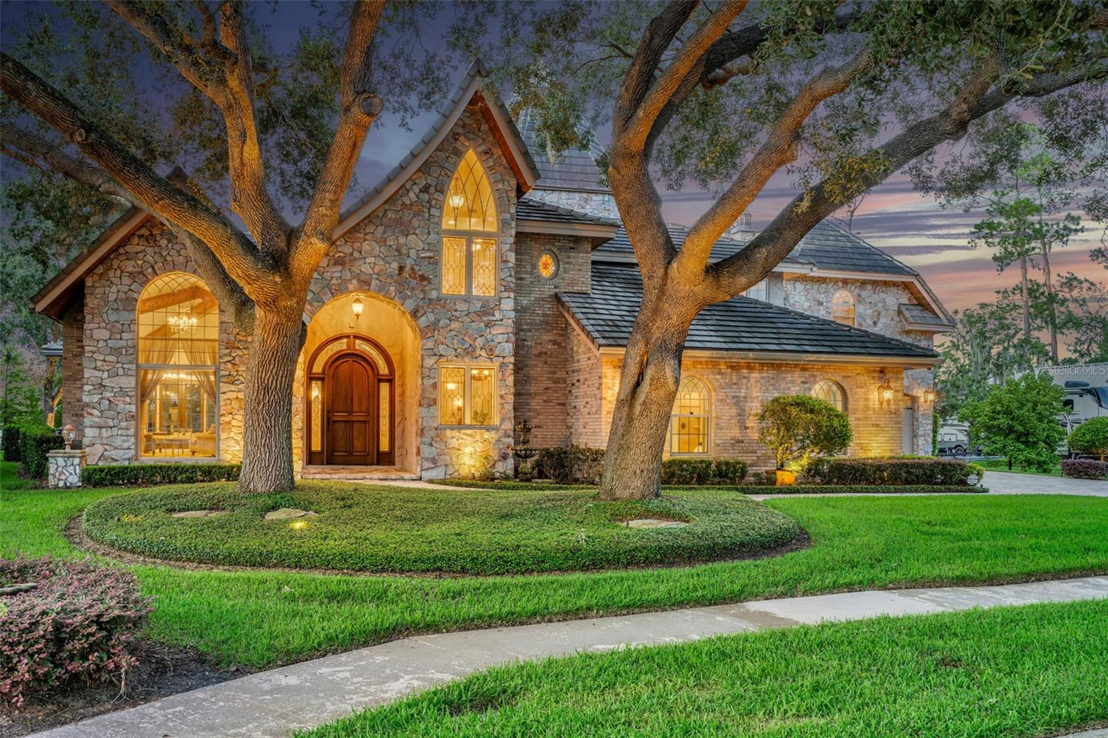 Experience the epitome of luxury in this Lake Front masterpiece, deemed Castillo Del Lago (Castle of the Lake) located on an exclusive cul-de-sac hidden amongst 3 lakes! Immerse yourself in the charm of Old-World European architecture and craftsmanship as you enter the home through a 9.5ft arched wood door with elegant side lights. Greeted by a grand staircase, soaring ceiling heights, rustic beams, exquisite stone accents, and panoramic lake views that will leave you breathless from every room. Indulge in the grandeur of the main home, offering 4 bedrooms and 4.5 bathrooms, polished marble floors, and dazzling chandeliers. Cedar ceilings add a touch of rustic elegance and warmth, with not just one, but two Primary Suites on each level of the home providing the ultimate in comfort and privacy. For the culinary enthusiasts, the chef's kitchen is a dream come true, custom cabinetry, stained glass lighting, exotic granite island, and elegant copper touches. A formal dining room sits just off the kitchen featuring a designer wine closet. Retreat to the spacious downstairs owner's suite boasting separate his and hers bathrooms and a walk-in closet with entrance through a hidden built-in door. The main level of the home provides a dedicated office space as well as 3 living areas for all your entertaining needs.
Indulge in luxury at every turn as you travel upstairs, with a private balcony off the second Owner's suite overlooking the lake. This incredible space offers a generous built-in closet and dressing room, along with a full marble bathroom featuring heated floors, whirlpool tub, and a multiheaded shower for the ultimate pampering experience.
But that's not all, embrace the unique charm of the 25 ft Cedar wood Turret circular room, cherry wood flooring, 2 additional bedrooms on the upper level, and a stunning wrought iron banister that adds a touch of elegance to the grand staircase. A separate guest quarters is offered above the 983 Sq/Ft 4-car Garage which has its own split unit AC providing heat as well.
The upstairs guest quarters overlook the lake and has ample room for sleeping and living as well as a full kitchen with gas stove, dishwasher, and bar top area for dining. A full marble bathroom with onyx tile and large walk-in closet along with 2 closets for storage make this room flexible enough to be an entertainment room or space for multigenerational families. Step outside of the main home and be captivated by the resort-like oasis that awaits you. Here you will find a sparkling pool with a fenced patio, hot tub with a mesmerizing water feature, sitting area fitted with a gas line for firepit, and your very own boat dock, perfect for endless adventures on the lake. Don't miss your chance to own this exquisite luxury home, where every detail has been carefully curated to provide a lifestyle that exceeds all expectations. Contact us today to schedule your private tour and witness the epitome of opulence!