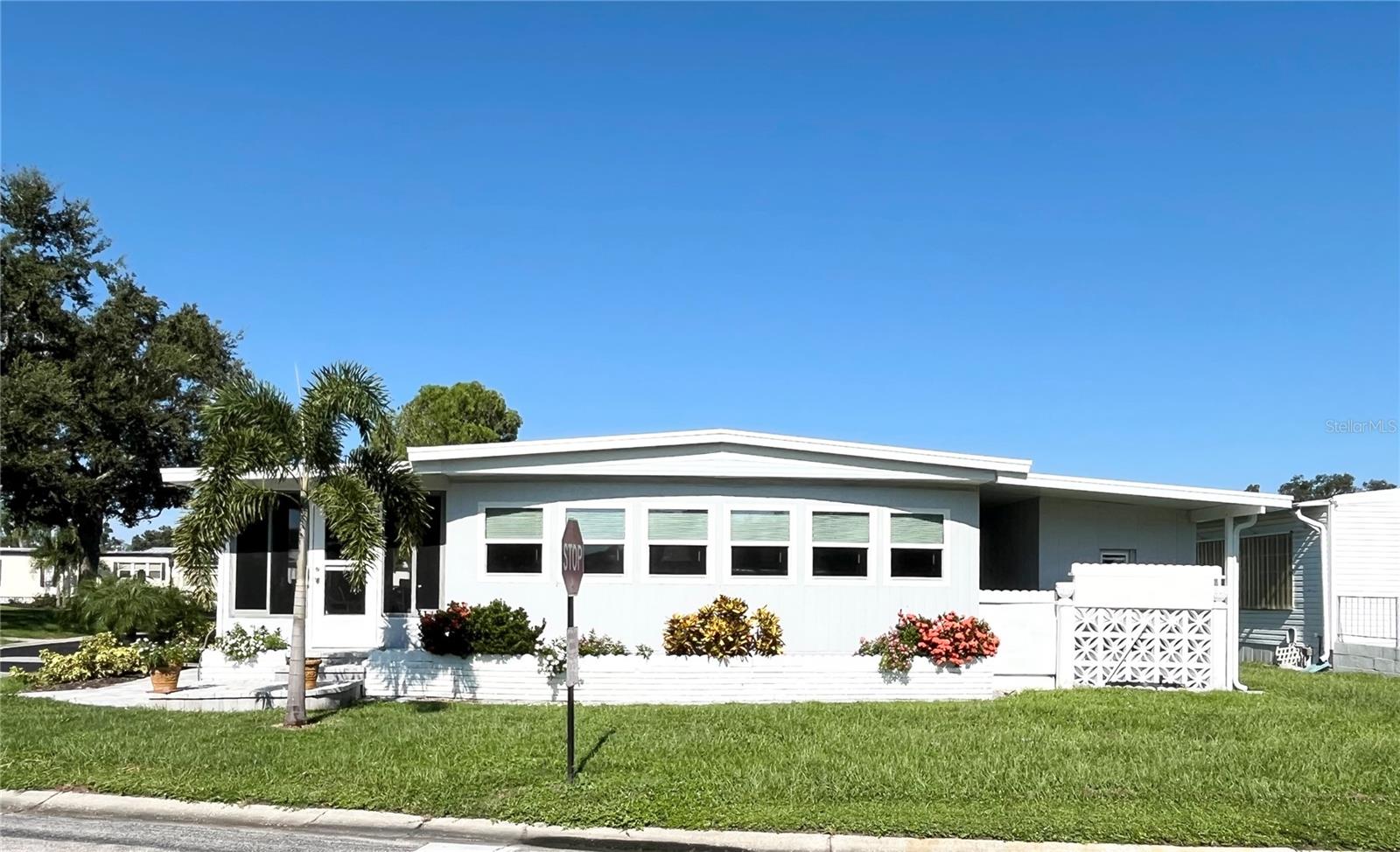 This spacious corner lot home is conveniently located within view of the clubhouse and close to both access gates in the ONLY Resident Owned Park in the City limits of Sarasota!! As you enter the main gate the beautifully landscaped Boulevard takes you right to this 2 bed / 2 bath home. The large living space has lots of windows overlooking the Boulevard and open space. The primary suite has its own private bath with step in shower and the guest bedroom has private access to the guest bath as well. The Florida room gives 200sf of additional living space and the owners have added an outdoor paver patio area and beautiful landscaping.
Additional upgrades and notes: Inside home home is drywalled/ 2018 Metal Roof Over (checked 7/2025) / Carport replaced 2025 / 2022 Double pane windows throughout with exception of couple to Florida room / Luxury Vinyl Plank flooring throughout 2022 / Square D electrical panel / Water Heater 2022 / electric has been added to the shed/storage.
The gated 90 acre community boasts a low maintenance fee with its vast amenities starting with the spacious Clubhouse outfitted with a full commercial cook kitchen, event stage, audio/visual, dance floor, state of the art fitness room, activities hall, library with books/movies/puzzles and a pool table. Outside recreation includes an extra large heated pool with a handicap ramp, a spacious kidney shaped hot tub, ample umbrella tables and lounge chairs and updated shower rooms. Oak trees shade the beautiful park area, picnic tables and a community grill. Additional amenities to enjoy are the community putt putt course, bocce ball, ping pong, horseshoes and corn hole. Oakwood Manor is a vibrant community with numerous social events and activities. Conveniently located adjacent to Legacy Trail and 12 newer pickle ball courts. Just a short drive to our crystal sand beaches, downtown area, the marina, fishing pier, local golf courses, shopping, variety of restaurants, the museum, SRQ airport, SMH and Doctors hospitals. Please note that Oakwood is a 55+, no pet, no motorcycle Park.