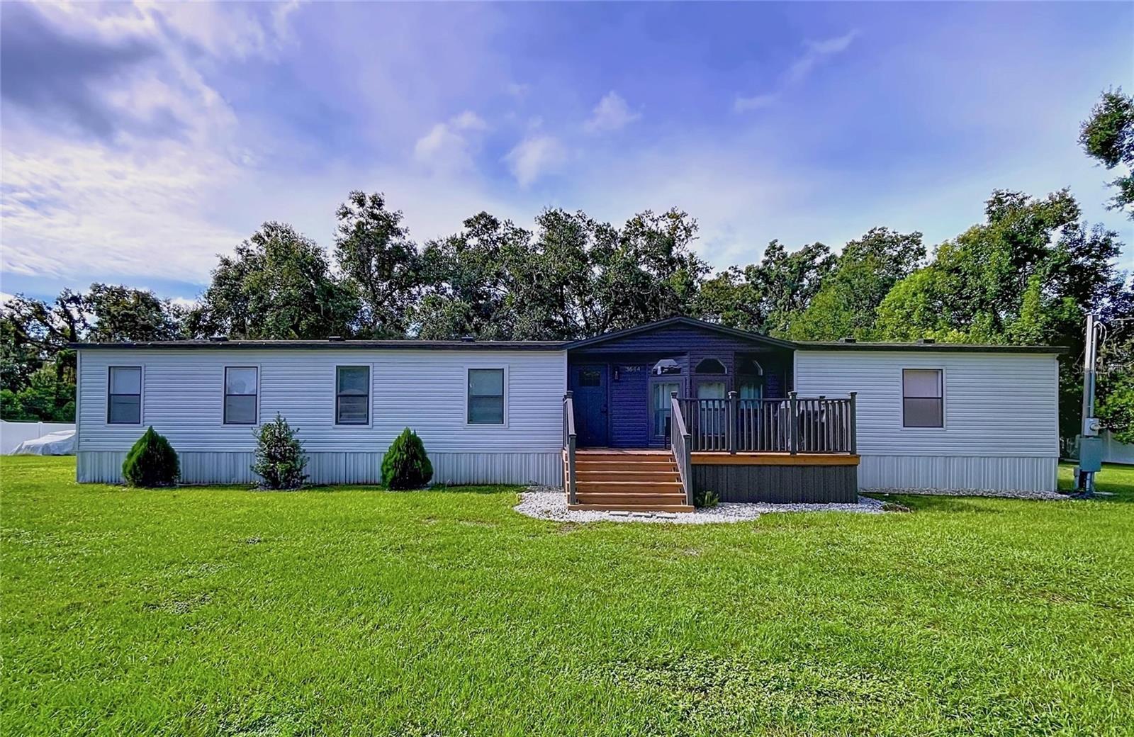 Welcome to this one-of-a-kind modern contemporary farmhouse retreat, offering 4 spacious bedrooms, 2.5 beautifully updated bathrooms, and just under an acre (.79) of land. Unlike any manufactured home you’ve seen before, this property sits on a solid concrete foundation and has been completely remodeled with luxury finishes and thoughtful upgrades. Inside, you’ll find stunning engineered wood floors, vaulted ceilings, 5 ¼ inch baseboards, custom accent walls, and a wide-open floor plan designed for comfortable living and entertaining. The kitchen is a true showpiece—boasting quartz countertops, updated cabinetry with an abundance of storage, a large island with additional space, a stylish counter-to-ceiling designer backsplash, stainless steel appliances, modern fixtures, and a pantry. The oversized primary suite features a walk-in closet and a spa-like en suite bath with dual sinks, a custom vanity, modern fixtures, has a potty training toilet, and an impressive walk-in shower. Three additional bedrooms provide ample space, each with newer ceiling fans and large closets, while the second full bath and powder room are tastefully updated as well. This home also offers a large indoor laundry room with sink, wireless Bluetooth speakers, a newer roof and water heater, plus a newly installed Culligan water softener and reverse osmosis system. Step outside and discover the crown jewel of this property—an incredible 1,636 sq ft workshop equipped with a fully installed lift, large air compressor, two massive roll-up doors, and brand-new wiring and electric panel, all neatly run underground in conduit. The yard is fully fenced with new wrought-iron fencing across the front and PVC fencing along the sides and back, offering both privacy and curb appeal. There is ample parking for RVs, boats, or commercial vehicles, making it ideal for hobbyists, small business owners, or anyone needing extra space. Perfectly blending the tranquility of a country setting with the convenience of nearby shopping, dining, and easy access to Tampa and Orlando via I-4, this home is truly move-in ready. Don’t miss your chance to own this remarkable property—schedule your private tour today!