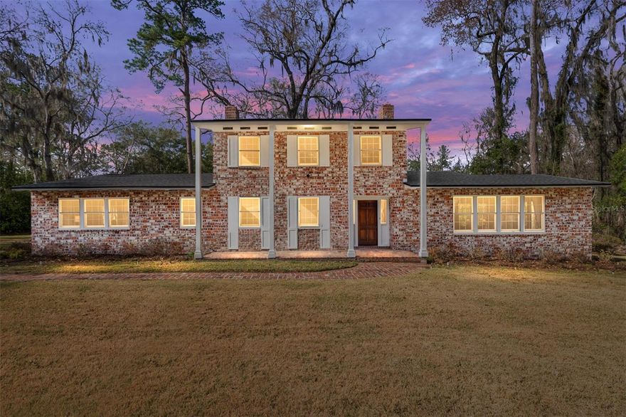 “A HOME BUILT WITH INTENTION” An “Old Florida,” mid-20th century home with a rich history, constructed of aged, repurposed bricks and old Florida cypress awaits you. This beauty has been in the same family since 1950. Here is her story: When this home was built, it was not within the city limits but is now in the heart of the city of Gainesville, FL. It is just 2.2 miles from the University of Florida, 6 minutes by car or easily bikeable. “Lazonby Acres,” comprised of 40 acres, was named after the original property owners. The neighborhood has long attracted professionals in the medical and other professions due to its close proximity to the University and downtown. It presently has seven other homes that sit on their own 5+ acres. With Possum Creek running below it; wildlife; beautiful aged magnolias, camellias, azaleas, oaks, and other native trees, this home is a nature lover’s dream. Still in place is a red brick, horse stable-turned-shed where the original owner kept his horses. He raised cattle, too, the evidence of which can still be seen by the presence of a cattle guard in the ground at the end of the driveway. The original owner acquired the home’s bricks from a bank building in Jacksonville, FL, that was being demolished. In collaboration with his architect, he used them to design a wythe wall for the house. This type of wall has brick as the exterior layer with another layer of brick as the interior wall. The paneled walls are made of cypress, a treasured wood from a significant old Florida tree. The home is comprised of two stories and a guest house that adjoins the two-car garage. The first floor contains a foyer with handlaid brick and cypress paneling, baseboards, and crown molding, features that are included in the rest of the house. There is also a very large Living Room and Dining Room and one home office/game room/playroom with built-in shelves that line one wall. There are two wood-burning fireplaces, one in the Living Room and one in the home office. Adjoining this home office is one renovated bathroom that leads into the large Primary Suite. The Kitchen and the adjoining Butler’s Pantry have recently been painted and re-built with all new appliances and wood cabinetry, new countertops, and upper cabinet lighting. A large Dining Room leads to an exterior side patio, which is perfect for entertaining. The Foyer has handsome stairs with new carpeting on the treads and landing. It leads up to two large bedrooms on the upper floor and a renovated bathroom. Another bedroom and new bathroom is in the guest house with a separate entrance. The windows were replaced circa 2005 and are double-paned. Newer renovations include a new roof ’24, new kitchen and appliances ‘25, newer washer and dryer, and new electrical service ’25 throughout the house, and participation in the re-paving of the private asphalt road that runs throughout the community, ‘25. This home now lives on in the 21st century, with an abundance of nearby shopping, food markets, entertainment, and the convenient location in which it sits. This well-loved home and its warm and cozy architecture have resulted in a significant piece of Gainesville history. It is truly an “Old Florida” country estate and a “HOME BUILT WITH INTENTION.”