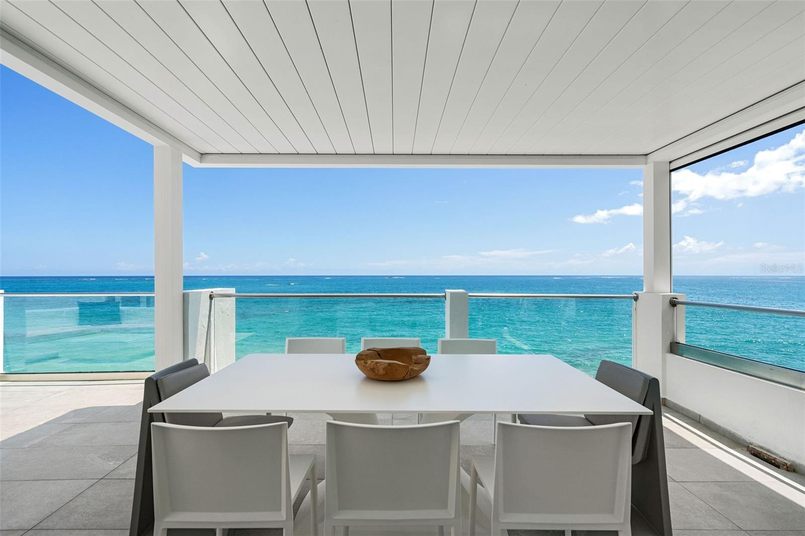 Under contract-accepting backup offers. Paradise awaits in the ultimate waterfront beach home. Located within the prestigious neighborhood of Ocean Park, San Juan’s most sought-after gated beach community, you’ll find this 5-bedroom, 5.5-bathroom, 4,863 square foot townhouse. Meticulously renovated over four floors, this architectural marvel features cathedral ceilings and open concept living. Built in 1998 by famed architect Mario Montilla and reimagined by Carlos Salazar in 2023, the design is focused on optimizing the privileged beachfront location and its unique surroundings.
Witness the dramatic beauty of the ocean from the moment you walk in, as 20-foot ceilings and a wall of windows create panoramic vistas of the Atlantic Ocean. Bright and airy, the first two floors of living space provide many options for entertaining or relaxing. The modern kitchen with quartz countertops, double dishwasher, Smeg and Kenwood appliances, faces the ocean. Custom oak woodwork and cabinetry in blue hues adorn the bar, complete with an industrial ice maker and a beverage cooler. A flex room and full bathroom currently outfitted as a music studio are the prefect home office or additional bedroom. Retreat to the upper floors where sumptuous double primary suites on each floor feature ensuite bathrooms with Grohe fixtures, custom Italian ceramic tile, double vanities, soaking tub, and steam shower. From the highest floor, experience the crowned jewel of this magnificent residence - the substantial terrace with 180-degree views of the beach and ocean. This perfect oasis is conveniently outfitted with a wet bar, grill, outdoor kitchen, outdoor shower, and Vondom furniture. A custom electric pergola is outfitted with lights and a windscreen to maximize comfort at any time of day. Every modern convenience has been considered in this masterfully recreated abode. This residence has full backup diesel generator, 2 water cisterns, electric storm shutters, and industrial grade garage doors. The garage fits 4 cars with a private entry directly into the home for discretion, security, and convenience. Garage is also customized for ample storage of all your beach gear. In addition, a private outdoor side yard can be outfitted with a jacuzzi, pool, or garden. This prime location is a mere 8 minutes from the Luis Munoz Marin International Airport, the city’s best schools, and the dynamic nightlife and gastronomy of Condado Beach.
Ocean Park is a dreamy, tree-lined beach community within the city, this rare find in the heart of it all can be yours today.