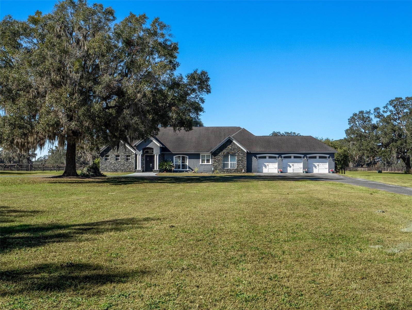 This 39.01-acre property in Ocala offers the perfect blend of tranquility and convenience, making it an ideal retreat for equestrian enthusiasts. Located just 10 minutes from both the World Equestrian Center and HITS, the property provides easy access to world-class equestrian events while maintaining a serene, quiet setting. The entire property is fully fenced, ensuring safety and security for both animals and residents. It features 8 paddocks and two turnout pens, all surrounded by mature oak trees that provide natural shade and privacy. The property also boasts deeded rights to a 3/4-mile professionally maintained thoroughbred training track and a 1-mile turf gallop, offering unparalleled access for training and exercise. For equine care, the property includes a well-maintained 8-stall center-aisle barn with sturdy wood frame construction, complete with a barn office, bathroom, tack room, wash rack, and feeding stations, as well as a separate storage shed for additional space. The custom-built home on the property features vaulted ceilings, elegant crown molding, and luxurious porcelain tile flooring throughout. With 3 spacious bedrooms, all ensuites, 3.5 bathrooms, and a bonus room perfect for an office or additional living space, this home is designed for comfort and style. The kitchen and living areas provide ample space for relaxation and entertaining, and the living room opens seamlessly to a covered back porch that extends the living space into the expansive backyard. A 3-car garage offers plenty of storage and parking space. Whether you're looking for a peaceful retreat or a property with exceptional equestrian amenities, this property offers the best of both worlds.