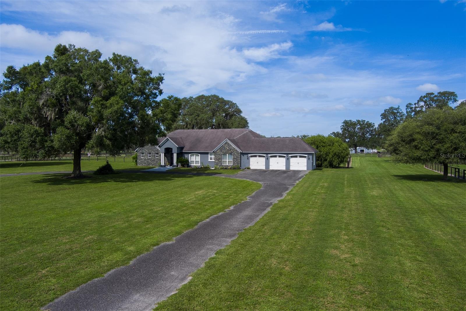 This 39.01-acre property in Ocala offers the perfect blend of tranquility and convenience, making it an ideal retreat for equestrian enthusiasts. Located just 10 minutes from both the World Equestrian Center and HITS, the property provides easy access to world-class equestrian events while maintaining a serene, quiet setting. The entire property is fully fenced, ensuring safety and security for both animals and residents. It features 8 paddocks and two turnout pens, all surrounded by mature oak trees that provide natural shade and privacy. The property also boasts deeded rights to a 3/4-mile professionally maintained thoroughbred training track and a 1-mile turf gallop, offering unparalleled access for training and exercise. For equine care, the property includes a well-maintained 8-stall center-aisle barn with sturdy wood frame construction, complete with a barn office, bathroom, tack room, wash rack, and feeding stations, as well as a separate storage shed for additional space. The custom-built home on the property features vaulted ceilings, elegant crown molding, and luxurious porcelain tile flooring throughout. With 3 spacious bedrooms, all ensuites, 3.5 bathrooms, and a bonus room perfect for an office or additional living space, this home is designed for comfort and style. The kitchen and living areas provide ample space for relaxation and entertaining, and the living room opens seamlessly to a covered back porch that extends the living space into the expansive backyard. A 3-car garage offers plenty of storage and parking space. Whether you're looking for a peaceful retreat or a property with exceptional equestrian amenities, this property offers the best of both worlds.