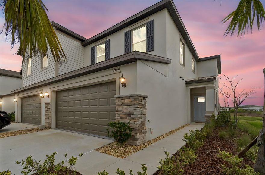 NEVER LIVED IN, FORMER BUILDER SALES MODEL, this beautifully upgraded townhome in the resort-style community of Mirada offers approximately 1,800 square feet of thoughtfully designed living space with 3 bedrooms, 2.5 baths, a second floor landing area, and a rare two-car garage. As a former model, the home showcases DESIGNER UPGRADES throughout, including custom accent walls, carefully selected finishes, and a polished presentation that immediately sets it apart. The open-concept main level features a spacious kitchen with abundant cabinetry, solid surface countertops, and a large center island that flows seamlessly into the dining and living areas, creating an ideal layout for both everyday living and entertaining. Sliding glass doors open to a covered lanai overlooking peaceful water views, offering a quiet outdoor retreat. Upstairs, the owner’s suite provides generous space, a large walk-in closet, and a well-appointed bath with dual sinks and a spacious walk-in shower. Two additional bedrooms, a full bath, and the second floor landing area create comfortable separation between living spaces. Mirada is known for its impressive resort-style amenities, including the well-known Crystal Lagoon, miles of walking trails, parks, playgrounds, and community gathering spaces designed for an active Florida lifestyle. The location also provides convenient access to Wesley Chapel’s premier shopping, dining, and entertainment, including Tampa Premium Outlets, The Shops at Wiregrass, and an abundance of top-rated medical facilities. Offering the rare opportunity to purchase a never-occupied former builder model, this home combines upgraded finishes, low-maintenance townhome living, and access to one of Pasco County’s most exciting master-planned communities.