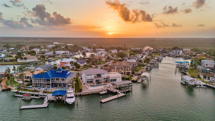 Where Architectural Elegance Meets Waterfront Luxury.
Welcome to 133 Via Capri, an extraordinary coastal estate where sophisticated design, advanced technology, and resort-style living come together seamlessly.

From the moment you enter through the twin glass entry doors, soaring 12-foot ceilings, custom tile inlays, curated designer lighting, and expansive walls of glass create an immediate sense of scale and refinement. The dramatic great room is filled with natural light and framed by serene views of the private pool and waterfront beyond, anchored by an 80-inch recessed Modern Flames fireplace with integrated LED lighting.

The open-concept layout flows effortlessly into the German-engineered chef’s kitchen, featuring custom SieMatic cabinetry, premium Miele appliances (including steam, speed, and multifunction ovens), concealed refrigeration, induction cooktop, wine storage, quartz waterfall island, granite sink, and statement pendant lighting.

The luxurious owner’s retreat offers tranquil water views, private lanai access, dual walk-in closets, and a versatile vaulted dressing or fitness space. The spa-inspired bath features frameless glass showers, rain heads, LED mirrors, and designer finishes. Guest accommodations are equally well appointed with beautifully updated baths and contemporary details.

Step outside to a true resort-style waterfront setting. The travertine lanai surrounds a heated pool and spa with sundeck, waterfall features, bubbler jets, and a fully automated iAquaLink system. Hurricane-rated electric roller shutters add convenience and peace of mind. The fully equipped summer kitchen includes granite counters, built-in grill, searing burner, beverage cooler, and bar seating for six—perfect for entertaining.

For boating enthusiasts, the property offers exceptional dockage with a covered lift for boats over 25 feet, a fixed dock for yachts over 45 feet, floating dock with aluminum gangway, integrated lighting, and surveillance. With direct access to open water, this is a rare opportunity to enjoy the best of New Smyrna Beach waterfront living.

133 Via Capri is more than a home—it is a statement of lifestyle, craftsmanship, and coastal sophistication.