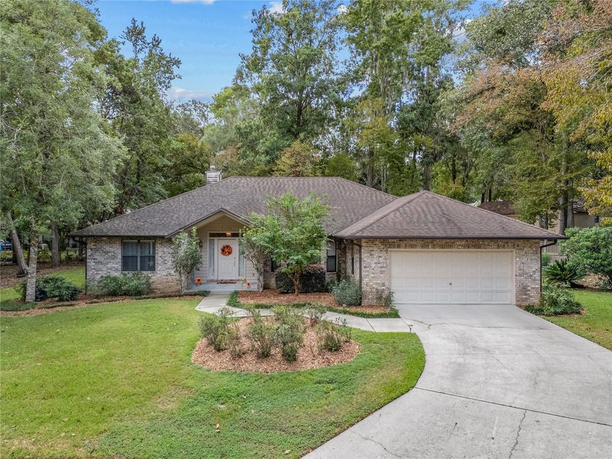 One or more photo(s) has been virtually staged. Welcome to 9329 NW 14th Place, a charming 3-bedroom, 3-bathroom pool home set on just under half an acre in the peaceful, non-HOA community of Oak Crest. Tucked away on a quiet cul-de-sac, this one-owner home has been lovingly maintained and is brimming with potential for easy cosmetic updates that will create instant equity for its next owners. The inviting curb appeal is framed by mature trees and a wide, pie-shaped lot that offers exceptional space and privacy.

Step inside to discover a thoughtfully designed split-floor plan anchored by a massive living room with soaring vaulted ceilings and a cozy wood-burning fireplace. The traditional dining room and a bright eat-in nook off the kitchen provide flexible spaces for gathering and entertaining. The kitchen is equipped with recently updated stainless steel appliances, and the home’s HVAC system has also been replaced for added peace of mind.

The spacious primary suite is a retreat of its own, featuring a large walk-in closet and an ensuite bath complete with a jetted Jacuzzi tub, a walk-in shower, and abundant natural light. Bedrooms two and three are generously sized, and the third full bathroom includes exterior access to the pool area, making it a convenient dedicated pool bath.

Outdoors, a triple sliding glass door opens from the living room to a covered patio overlooking the screened-in pool. The pool area is well-maintained with an updated pool pump and filtration system, a cleanly surfaced deck, and a solar heating setup for extended swim seasons.
Practical features include an interior laundry room with a utility sink and the washer and dryer already in place. The wide cul-de-sac lot provides extra space between neighbors along with a generous cleared yard area for recreation or gardening.

Oak Crest is ideally located in west Gainesville, zoned for highly rated schools and just a short drive to shopping, dining, and recreation in the Jonesville and Tioga areas. It offers quick access to I-75 via Newberry Road, is minutes from UF Health/Shands and North Florida Regional hospitals, and only about 15 minutes from the University of Florida.

This is a rare opportunity to own a well-cared-for home in a sought-after location, ready for your personal touch to unlock its full potential.