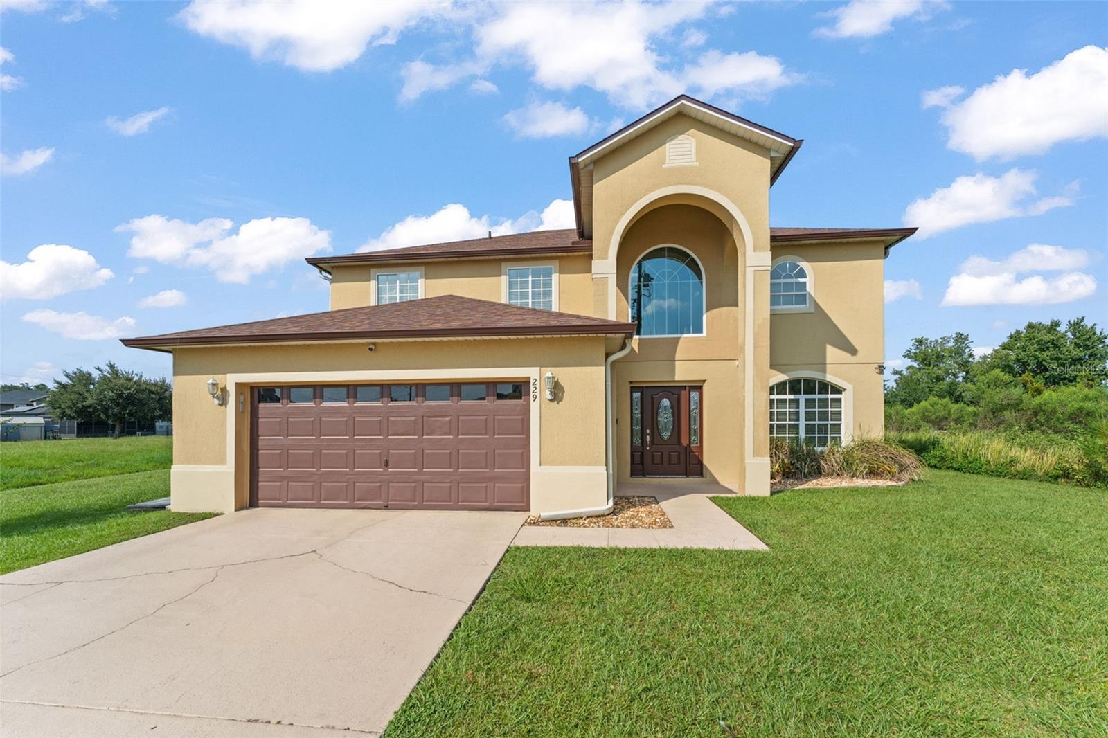 **This house comes with a REDUCED RATE through the seller's preferred lender. This is a lender-paid rate buydown that reduces the buyer's interest rate and monthly payment.** Welcome to a beautifully designed two-story home offering nearly 2,900 square feet of refined living space on almost a quarter acre in the heart of Kissimmee. With 4 spacious bedrooms, 3 full bathrooms, a versatile loft, and a 2-car garage, this property combines elegance, functionality, and comfort. As you arrive, a stately arched covered entry with a large transom window above the front door sets the tone for what lies beyond. Step through the rich dark wood entry door with sidelites, and you're greeted by soaring ceilings, a welcoming living room, and an impressive staircase leading to the second floor. Decorative pillars elegantly frame the formal dining area, perfect for hosting gatherings and creating lasting memories. The open-concept kitchen and family room offer both style and convenience. Enjoy white cabinetry with crown molding, stone countertops with bar seating, stainless steel appliances, a chic backsplash, and a cozy breakfast nook. The adjacent family room is flooded with natural light from multiple windows and a sliding glass door that opens to the screened patio. Also on the main level, you'll find a full guest bathroom with a tub/shower combo, a convenient indoor laundry room, and access to the garage. Upstairs, the primary suite is a true retreat, featuring laminate flooring, dual closets, and a luxurious en suite bathroom with floor-to-ceiling modern tile, a walk-in shower, a separate soaking tub, and a dual-sink vanity. Three additional guest bedrooms with built-in closets share a third full bathroom, also with a tub/shower combo. The upper-level loft area is a standout feature – a bright, open space overlooking the living room and entryway, ready to become your home office, playroom, media center, or anything you can imagine. Step outside to the screened-in patio with a ceiling fan, where you can relax and enjoy the peaceful grassy view beyond – your private slice of Florida tranquility. To top it off, this home features a new A/C system installed in 2024, ensuring year-round comfort and energy efficiency. Don’t miss the chance to make this stunning, move-in-ready home yours. Schedule a showing today and fall in love with everything 229 Amesbury Ln has to offer!