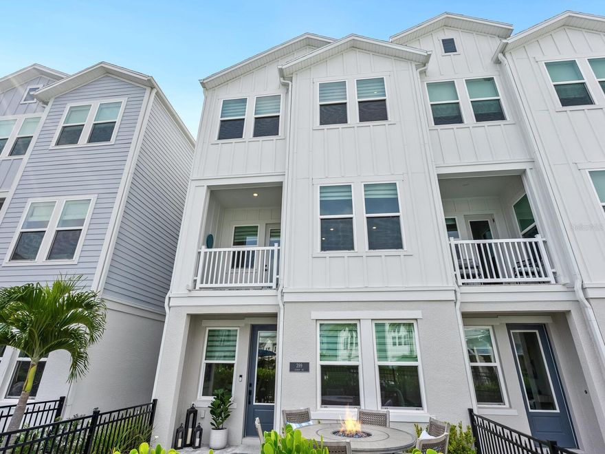 This modern coastal townhome delivers refined design, luxury finishes, and an exceptional Sarasota lifestyle in one of the city's most vibrant downtown locations. Situated near Downtown Sarasota, Payne Park, and the Legacy Trail bike path, the residence also enjoys a prime position directly across from the community pool and leisure lawn, complete with cornhole and gathering space. 
The main living level is thoughtfully designed for both everyday living and entertaining. The chef's kitchen is a standout, featuring floor-to-ceiling white wood cabinetry with crown molding and brass hardware finished with a white quartz countertop. Modern glass and brass pendant lighting complements the kitchens centerpiece island, which provides additional seating and storage. A custom tile feature wall frames the apron sink, positioned beneath two large windows that flood the space with natural light. The adjacent dining area is elevated by a striking wall of mirrors with wood trim, while the family room showcases a wall of windows overlooking the pool and lawn area. A private balcony extends the living space and provides the perfect space to relax. On the lower level, Bedroom 2 is currently configured as a home office and offers exceptional flexibility with a full bathroom, closet, built-in shelving with Murphy bed. This level also provides access to a spacious stone patio with iron fencing and a gated entrance, ideal for outdoor enjoyment. Completing this floor is a 2-car garage equipped with an EV charging station. On the third floor you will find a generous sized primary bedroom with a well-appointed ensuite bathroom that includes a dual sink vanity with custom framed mirror, large walk-in shower with glass enclosure and an oversized walk-in closet with built-in shelving. Bedroom 3 also includes its own ensuite bathroom, offering comfort and privacy for guests or family members. A conveniently located laundry closet completes this level. With its sophisticated coastal aesthetic, thoughtful layout, and unbeatable downtown Sarasota location, this townhome offers a rare opportunity to enjoy luxury living with access to the very best of the city's cultural, recreational, and outdoor amenities.