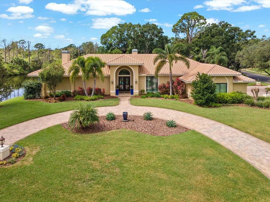 Step into a world where refined design meets relaxed Florida living. This stunning 4-bedroom, 4-bathroom estate rests gracefully on just over an acre in a quiet cul-de-sac within an intimate luxury community offering a dock and boat ramp on Salt Lake, with Gulf access through the scenic Anclote River. From the moment you arrive, the pavered circular drive and lighted pillars welcome you home to a place that balances elegance, comfort, and possibility.

Inside, marble floors with detailed carpet inlays set the tone for timeless sophistication. High ceilings, crown molding, and abundant natural light create a sense of openness throughout the 3-way split floor plan. A dedicated office or flex space allows for productivity or creative pursuits, while the formal living room, family room, and primary suite each feature a cozy wood-burning fireplace—perfect for quiet evenings or lively gatherings. The heart of the home, the kitchen, boasts quartz countertops, stainless appliances, and a sunny breakfast nook with views of the tranquil pool courtyard and pond.

The primary suite is a retreat unto itself, with a spacious sitting area overlooking the courtyard and pond, dual sinks with a private vanity, a garden tub, and a doorless walk-in shower in the en suite. The expansive walk-in closet offers custom built-ins with his-and-hers sides, while the bedroom’s fireplace adds a touch of warmth and romance.

Outdoors, imagination turns to reality with a professionally landscaped, caged courtyard designed for both serenity and celebration. The solar-heated saltwater pool with spillover spa invites year-round enjoyment, framed by travertine decking, an outdoor kitchen with granite counters, stainless sink, drawers, and storage, and a full pool bath for convenience. Beyond the screened lanai, you’ll find space to cast a line into your private pond or stroll across the street to fish on Salt Lake itself.

Practical luxury continues with a 3-car oversized garage featuring race-deck flooring, workshop space, and storage closet. The side-entry and circular drives enhance functionality and curb appeal, while the tile roof and custom front door add architectural charm. Over the past several years, thoughtful upgrades have included double-pane impact windows and sliders, an insulated garage door, pool resurfacing and new tile, irrigation and pool pump replacements, and a new pool cage—all ensuring that this home’s beauty is matched by its quality and care.

Less than half a mile from the Pinellas Trail, this residence is more than a home—it’s a lifestyle, where every day offers a new way to live, play, and dream.