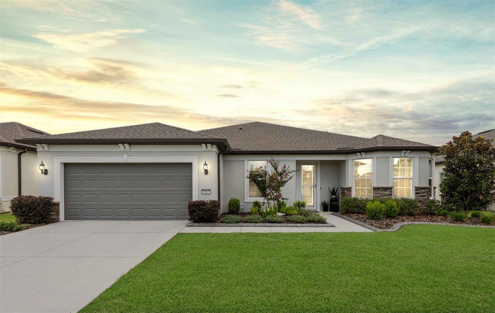 Experience effortless resort-style living in this beautifully appointed Stardom model—featuring 2 bedrooms, 2.5 baths, and a versatile Den—set on a premium lot with serene, unobstructed green space views. Nestled on a quiet, no-through-traffic street in the Wellington neighborhood of Stone Creek, this nearly 2,300-square-foot home offers thoughtfully designed living in a gated 55+ golf course community known for its exceptional amenities and vibrant lifestyle. This stunning home features a unique split floorplan with two spacious primary suites, each offering privacy and a peaceful retreat, and a flexible den adding versatile space ideal for a home office, creative hobby room, or a quiet reading nook. The well-appointed open-concept layout is enhanced by high ceilings, LED downlighting, luxury vinyl plank flooring, and a striking double tray ceiling in the gathering room that adds architectural elegance. Every detail in this home—from the lighting to the layout—has been curated to create a warm, welcoming environment that feels both refined and livable. Expansive 15-foot-wide retractable sliding glass doors flood the living area with natural light and create a seamless indoor-outdoor connection to the spacious sunroom—complete with all-season sliding windows, screens, and ambient LED downlighting. Just beyond, a separate screened-in birdcage lanai offers the perfect retreat for morning coffee or evening relaxation, surrounded by peaceful nature views. The gourmet kitchen is a true showpiece, where form meets function in grand style. Anchored by a nearly 12-foot island, it features gleaming granite countertops, a full-height tiled backsplash, and 42” cabinetry with lower pull-out drawers for seamless organization. Built-in KitchenAid appliances—including a vented range hood and dual full-size ovens—elevate culinary possibilities, while the spacious walk-in pantry ensures every ingredient has its place. The primary owner’s suite is a serene sanctuary, where a trio of windows frames peaceful views of nature, and a generous walk-in closet provides optimal storage space. The spa-inspired ensuite features a granite-topped dual-sink vanity, a large Roman-style shower adorned with glass tile accents, and a transom window that bathes the space in natural light. Designed for everyday comfort and convenience, this home offers generous storage throughout—from the oversized laundry room and coat closet to a utility room with space for an additional refrigerator. Smartly designed extras include a built-in workspace in the gathering room, a practical mud room for daily routines, a fully fenced backyard, and an extended garage with space for hobbies, storage, or a golf cart. CAT 6 wiring and additional electrical outlets have been strategically added throughout, enhancing connectivity and everyday ease. Step beyond this thoughtfully designed home into a vibrant community where every day feels like a retreat. With 24/7 gated security, Stone Creek offers peace of mind and a lifestyle rich in comfort and connection. Enjoy resort-style amenities including heated pools, a full-service spa, pickleball, tennis, and bocce. A dedicated lifestyle team curates engaging events, while the nearby golf course, pro shop, and on-site restaurant provide the perfect setting to unwind and socialize. Make your move today and experience an ideal blend of elegance and active living.