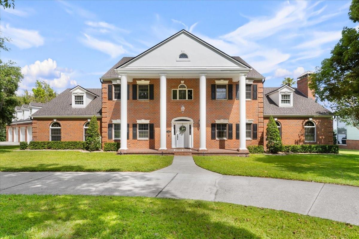 ***PRICE REDUCTION*** Amazing Winter Haven Executive Home on 1.86 Acres with Lake Eloise Frontage! Welcome to this elegant two-story home nestled on nearly 2 acres in a serene, park-like setting on Lake Eloise. From the moment you step into the grand foyer—with its sweeping curved oak staircase, wainscoting, and a stunning Palladian window—you'll appreciate the timeless craftsmanship throughout. The spacious living room centers around a large fireplace with a custom-designed Georgian mantel and matching built-in bookcases. In the formal dining room, you’ll find exquisite built-in cabinets, while the private library features rich, custom cherry wood bookcases. The gourmet kitchen is a chef’s dream, complete with a Jenn-Air double ovens, built-in breadbox, appliance garage, and cutting boards—all seamlessly integrated. The kitchen and breakfast area with an expansive 15x31 feet of space, ideal for both cooking and entertaining. Additional features include insulated Anderson casement windows, a dramatic two-story Greek Revival front portico, and wide 4-foot hallways throughout. Thoughtful details such as keystone window headers, dentil molding under the eaves, and decorative quoins on the brick front elevation add architectural charm. Enjoy your heated Infinity saltwater Pool with stunning views of the shaded backyard and Lake Eloise. Practical touches abound, including an underground dog fence, irrigation system, deep well with water conditioning, dual hot water heaters (including one with a heat recovery unit), and a dual-zone A/C system. The interior also boasts a well-equipped laundry room with cabinets, a built-in ironing board, and a laundry chute. Storage is plentiful, with easily accessible closets and attic spaces. Architectural features continue indoors with transom windows above the archways in the dining and living rooms, and a beautiful sunburst elliptical window with sidelights welcoming guests at the front door.